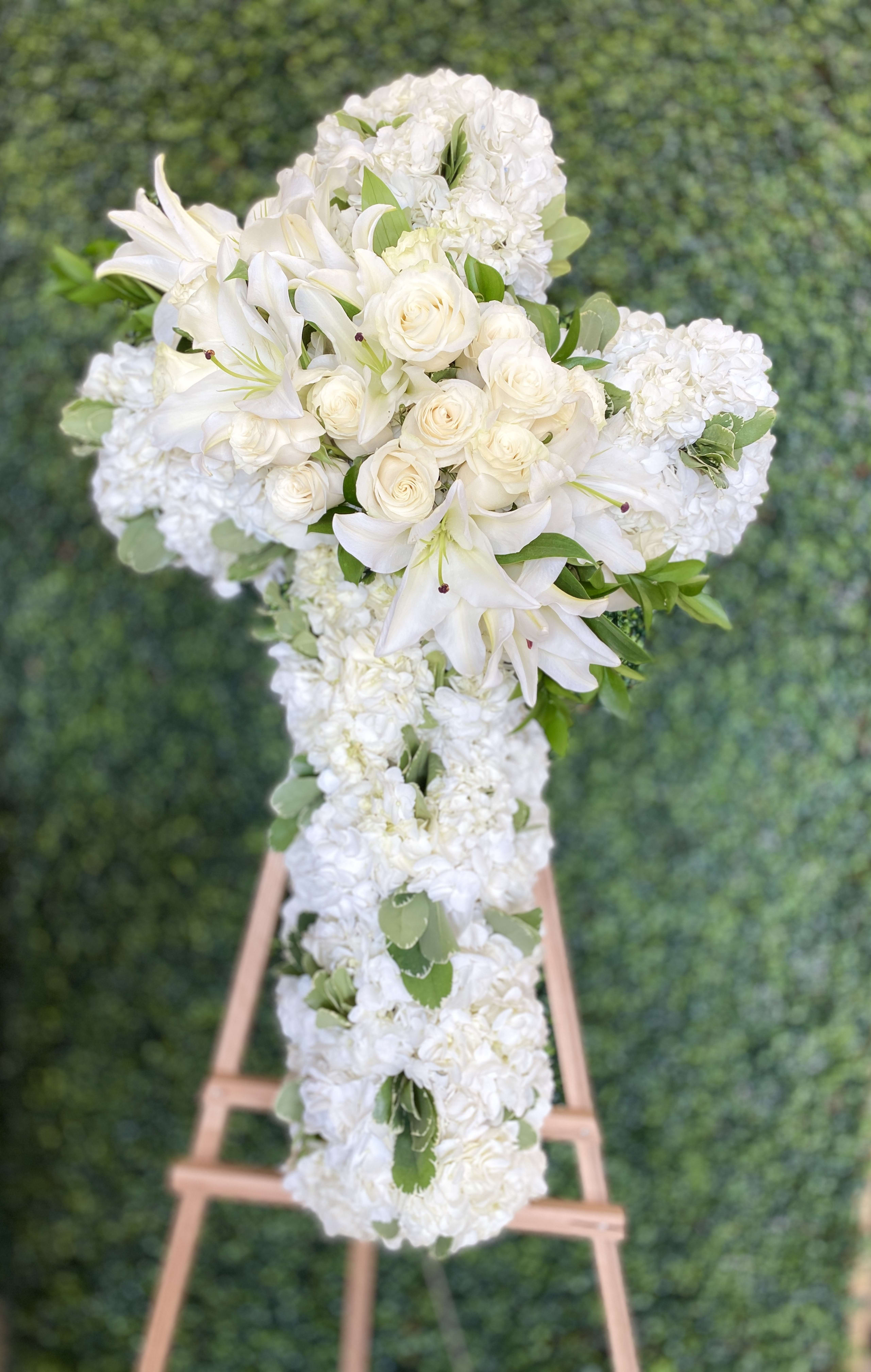 White floral wedding arrangement on an easel with lilies and roses