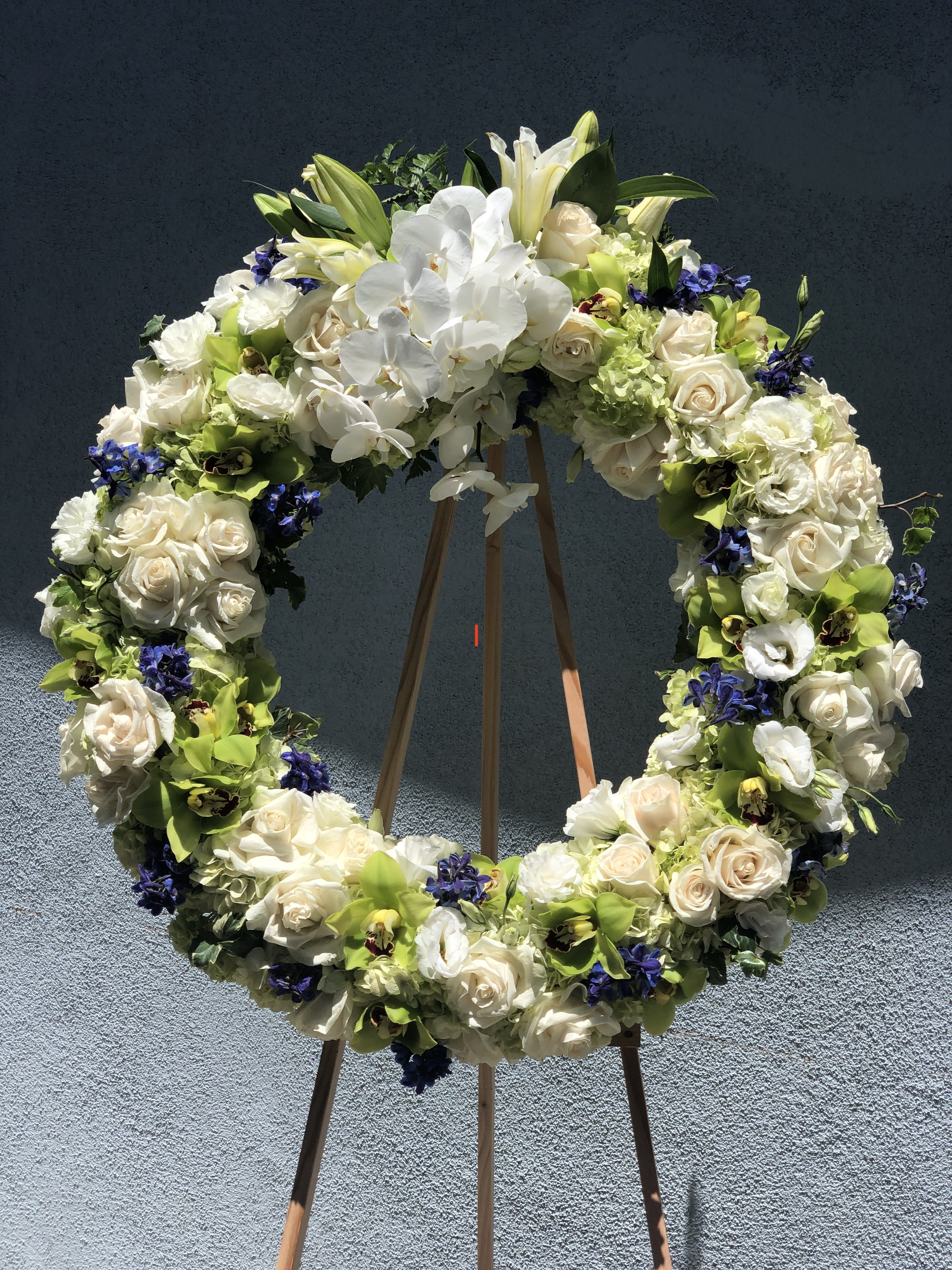 Large floral wreath on a wooden stand with white roses and orchids