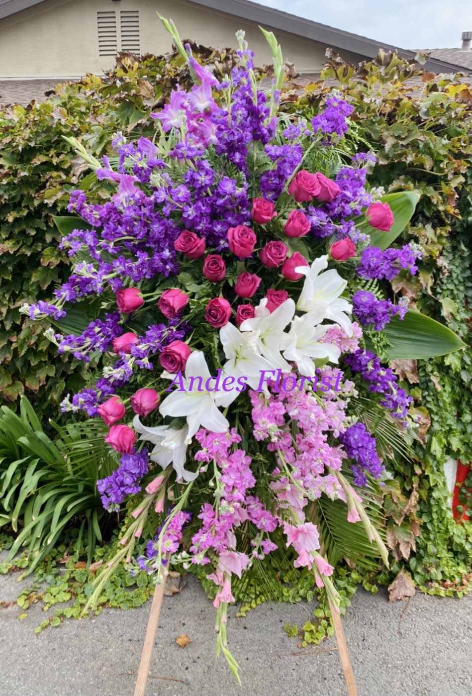 Large standing floral spray with pink roses, white lilies, and purple flowers