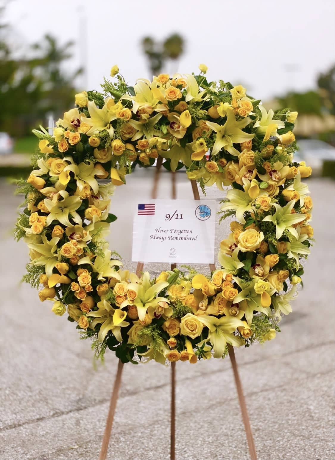 Yellow floral wreath on an easel with a 9/11 remembrance sign