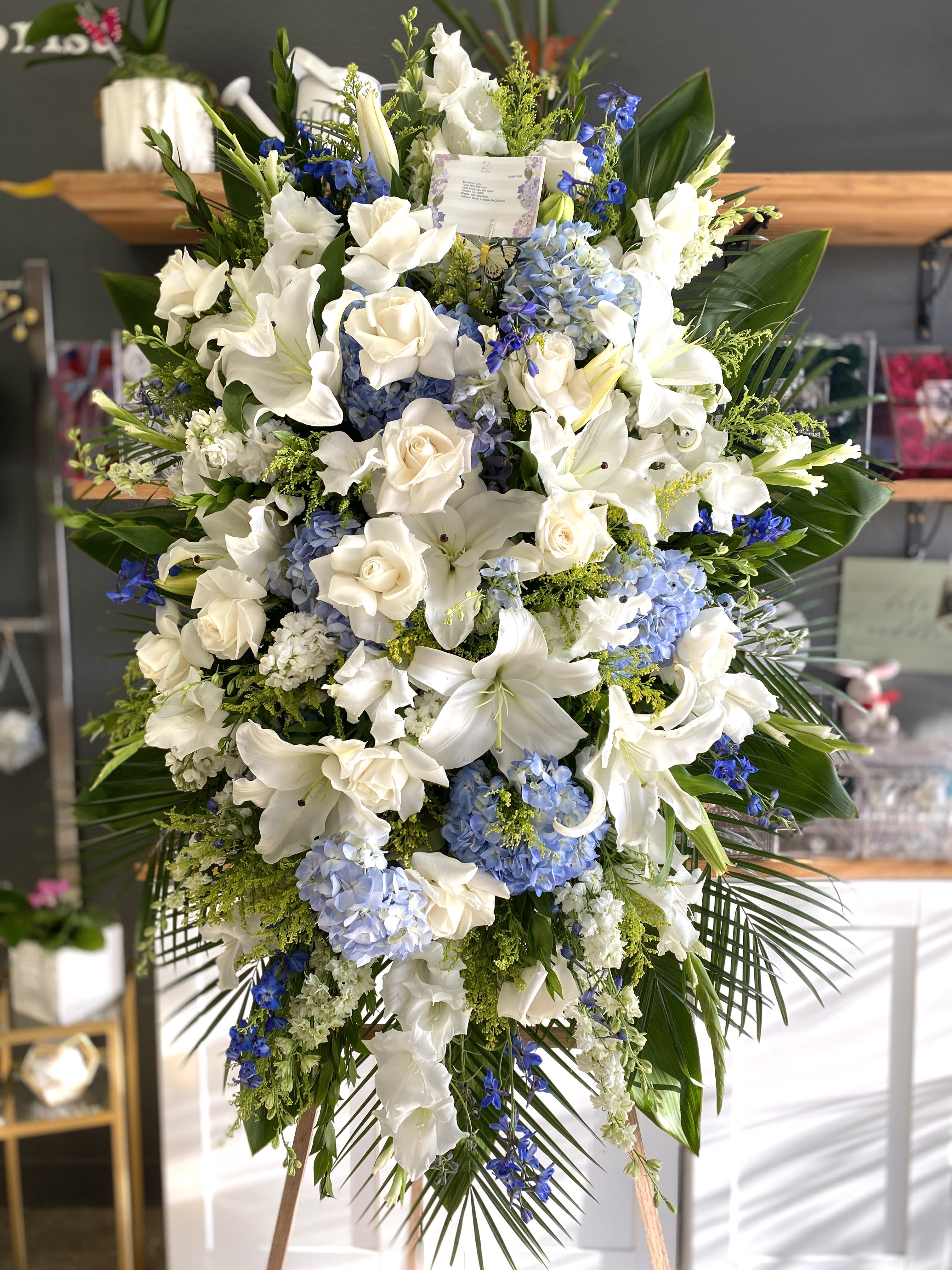 Large white and blue floral standing spray on an easel