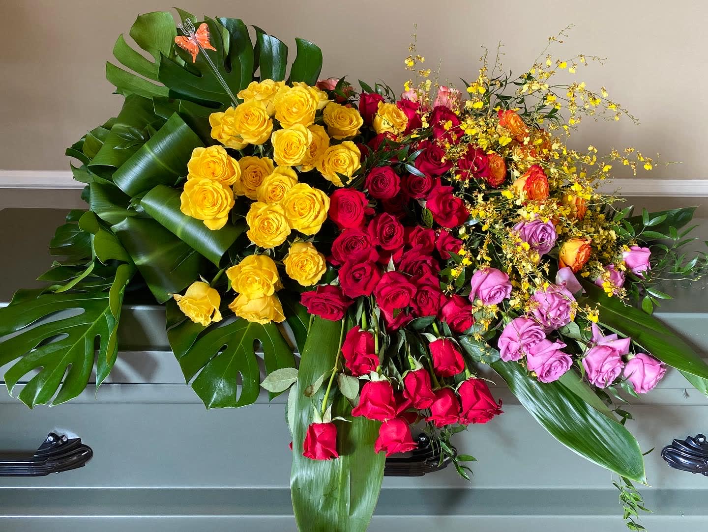 Large arrangement of multicolored roses with tropical leaves