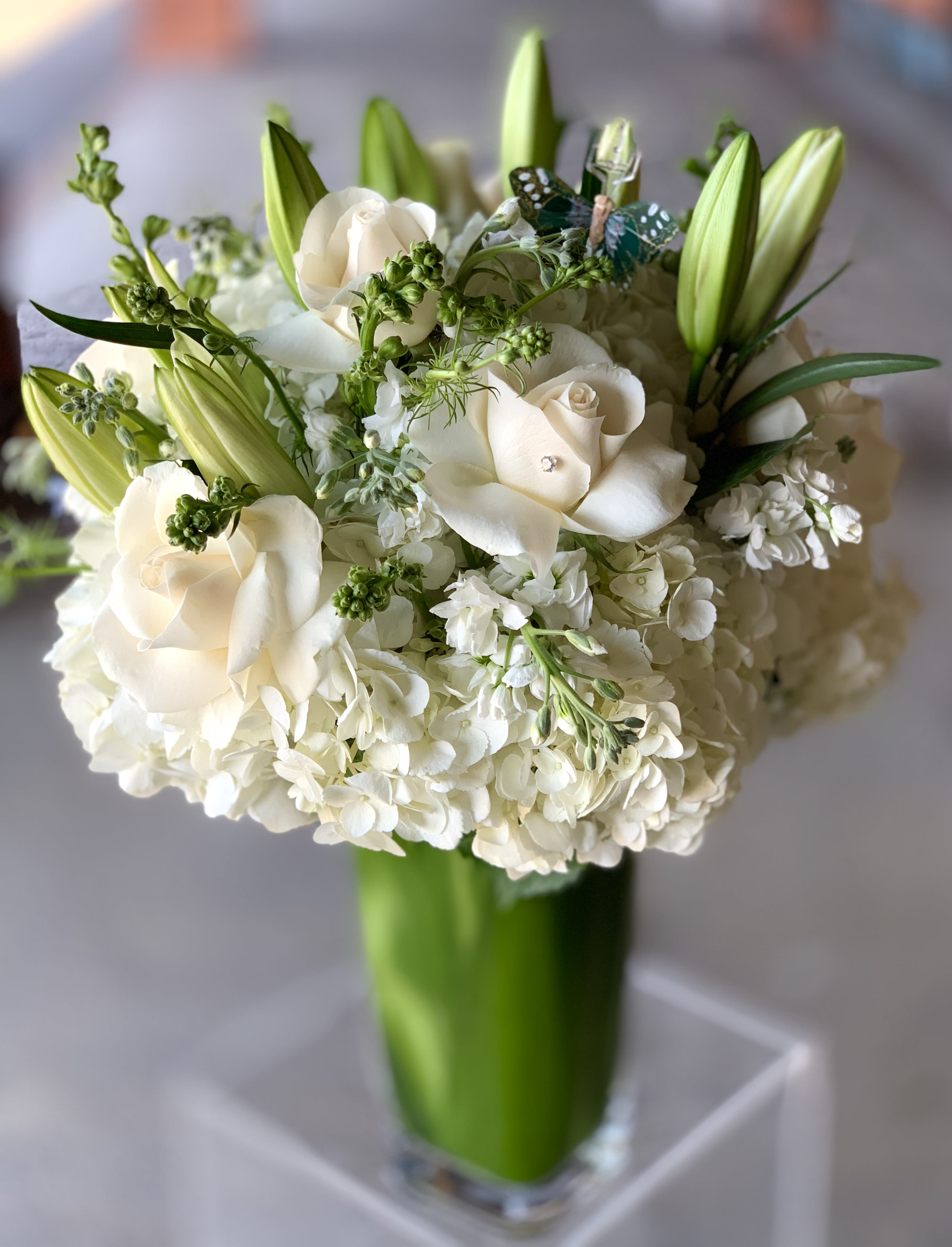 White roses and lilies arranged in a tall glass vase