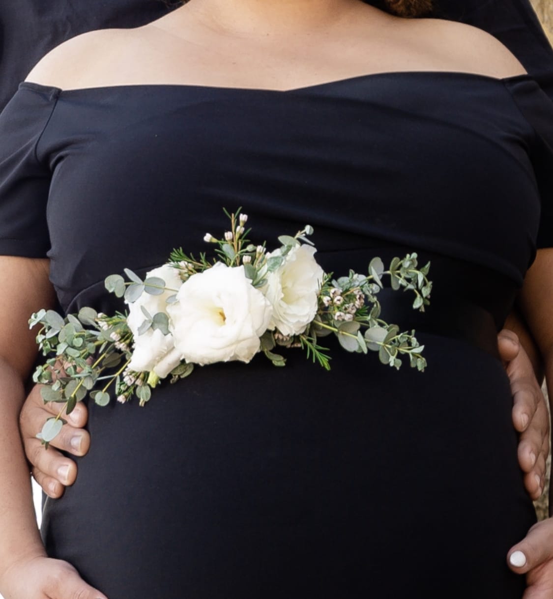 White floral corsage with greenery worn at the waist