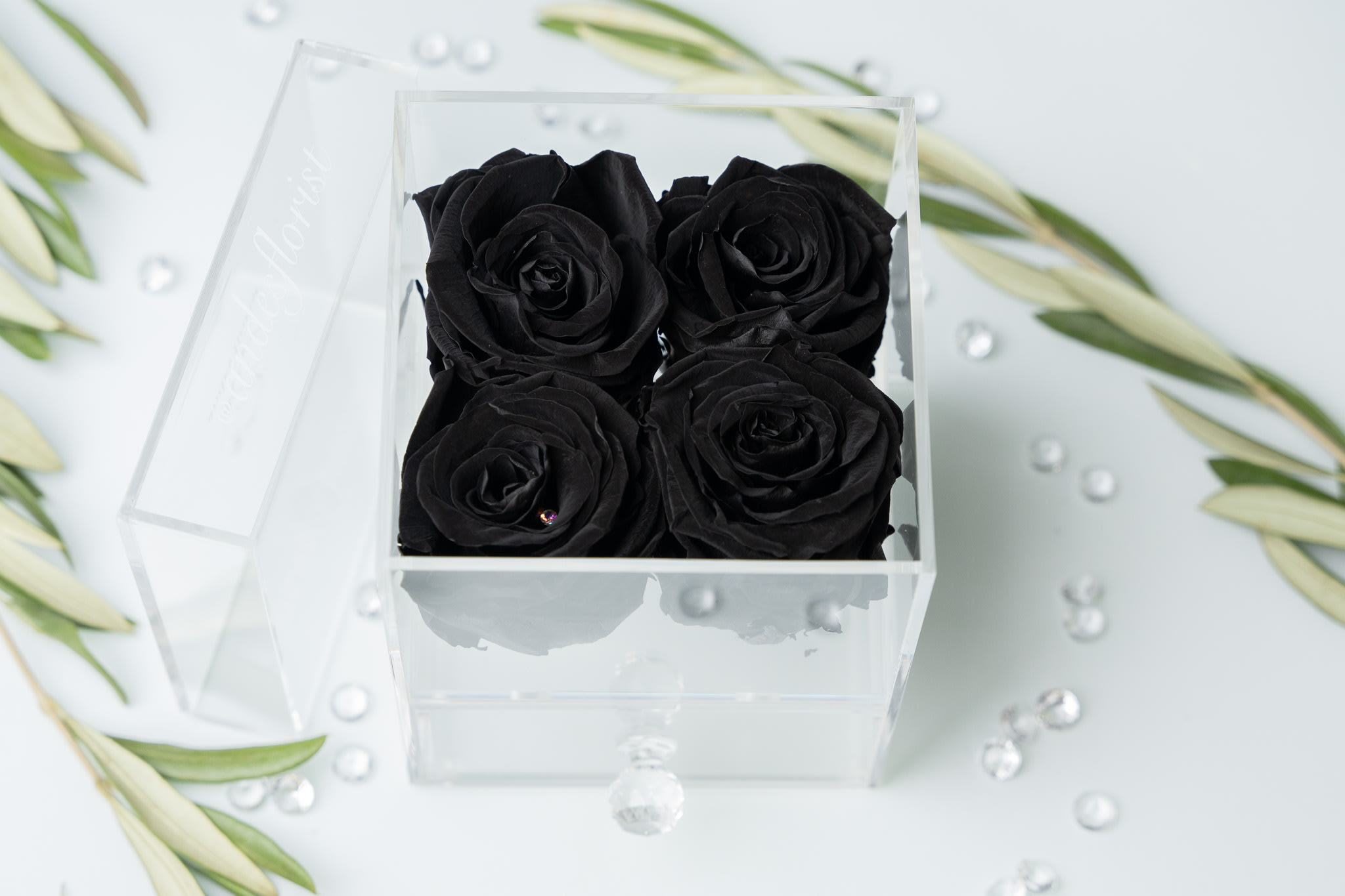 Four black roses in a clear square box