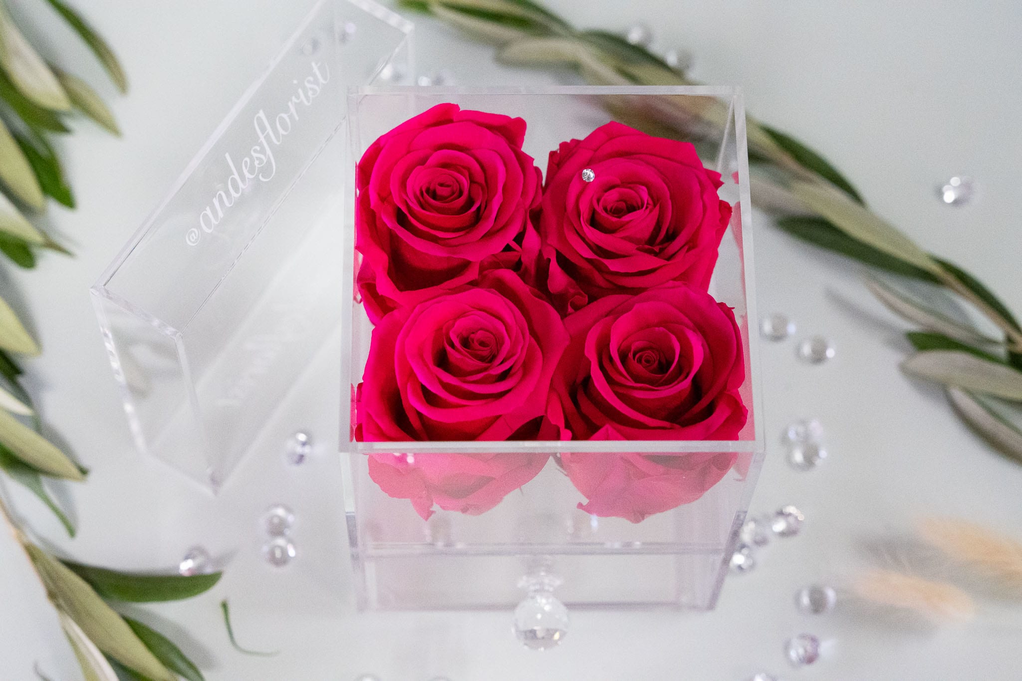 Four hot pink roses in a clear acrylic box