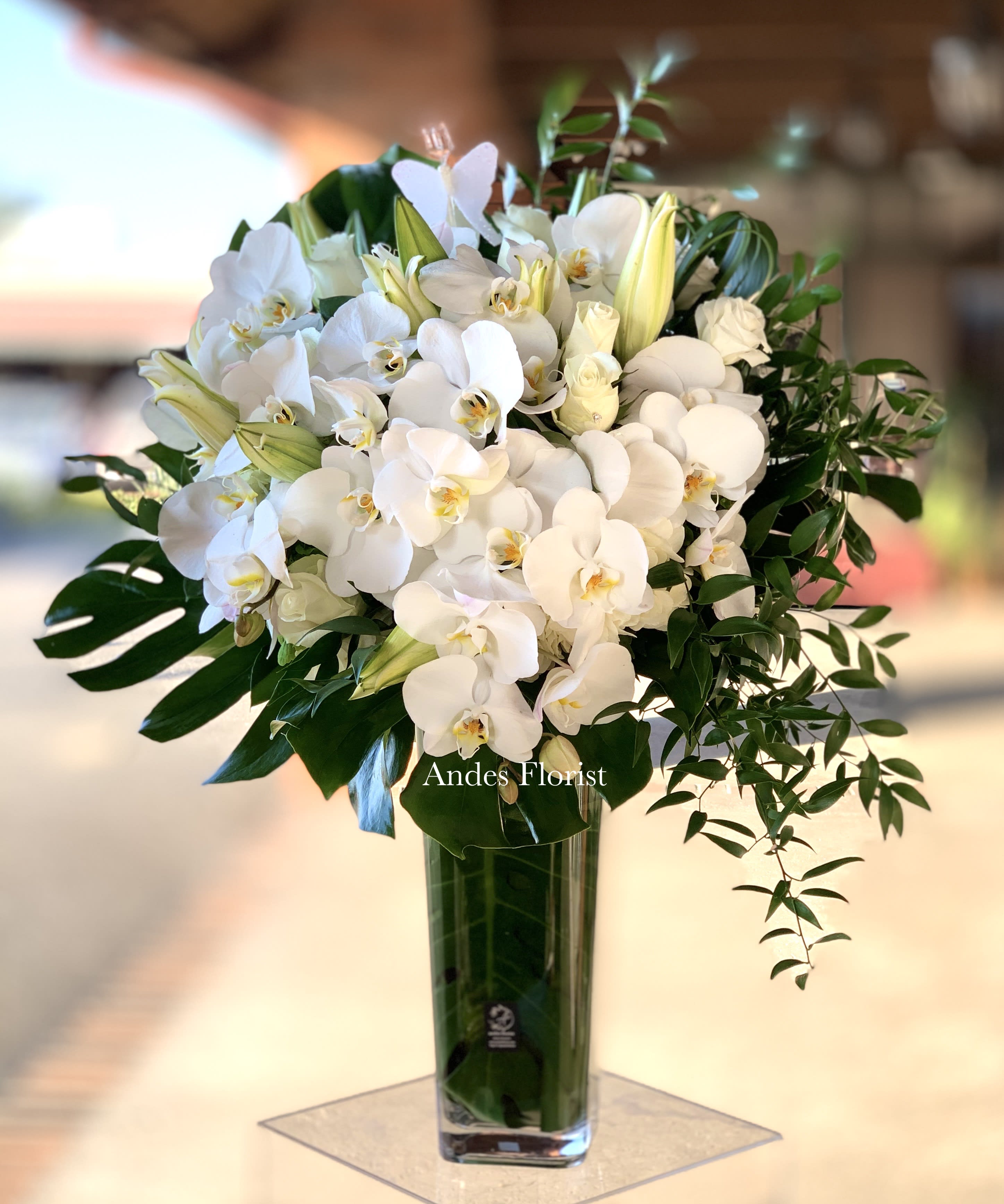 White orchid and lily arrangement in a tall glass vase