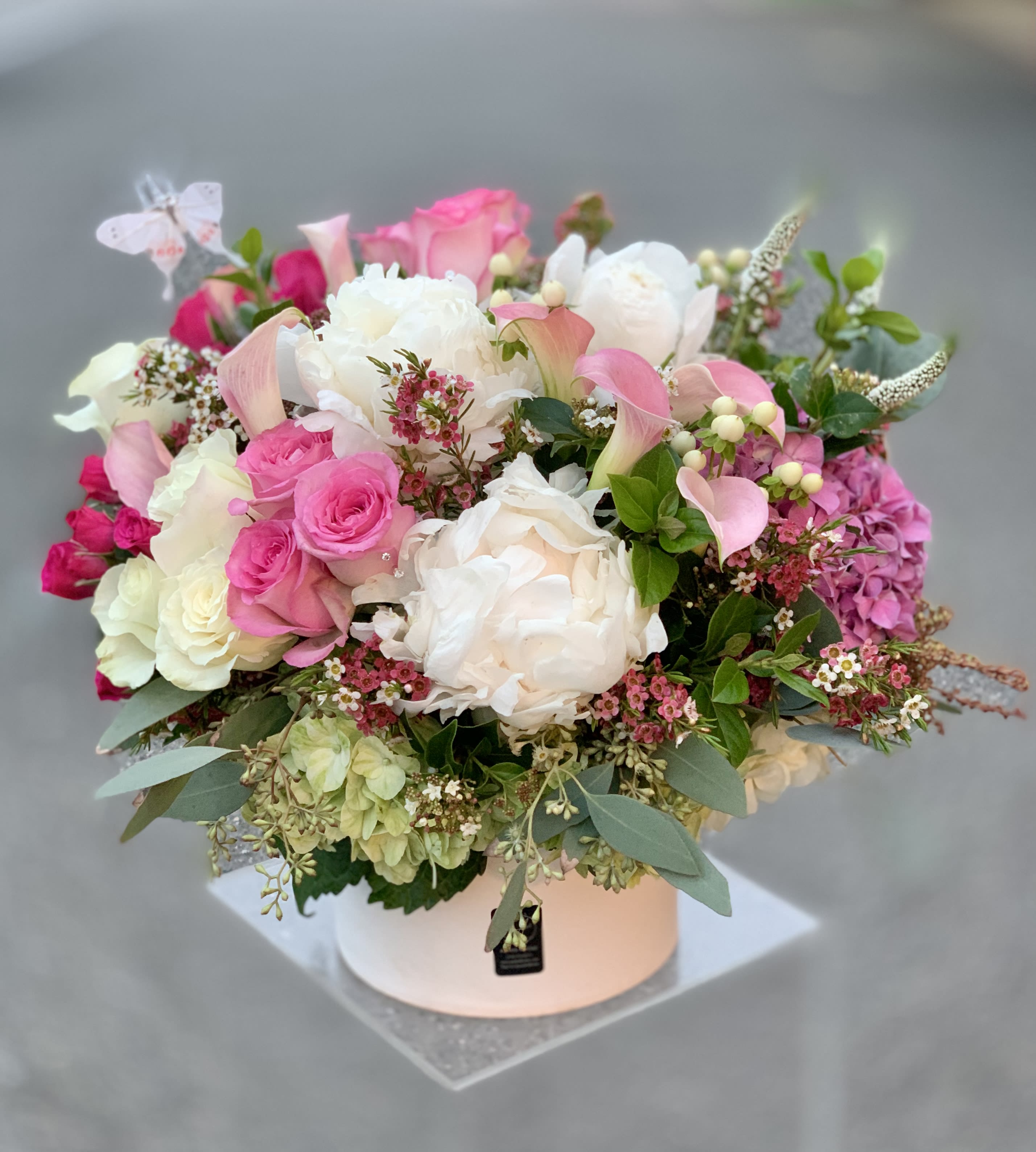Pink and white mixed flower arrangement in a round box