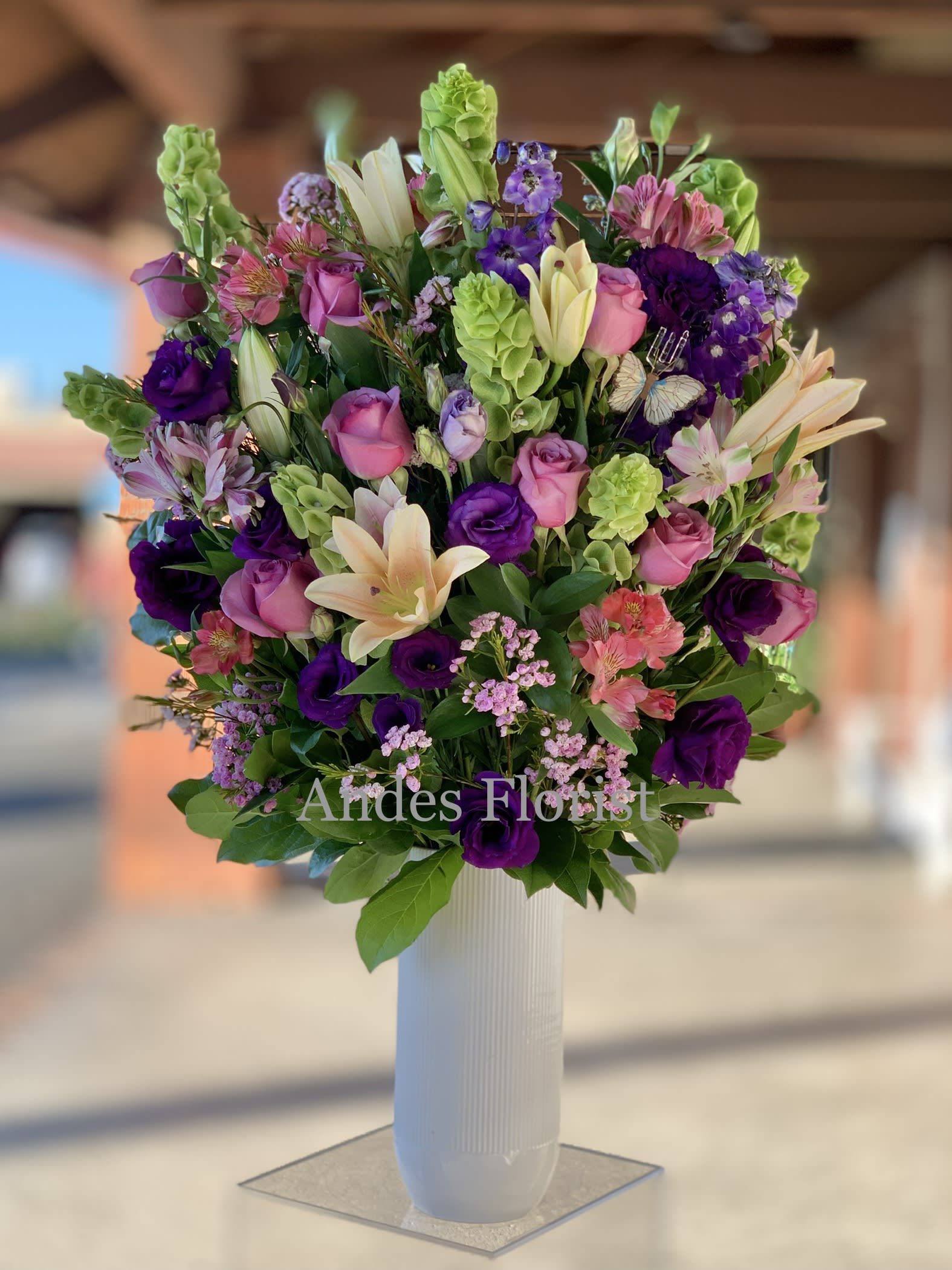 Mixed bouquet of pink, purple, and cream flowers in a white vase