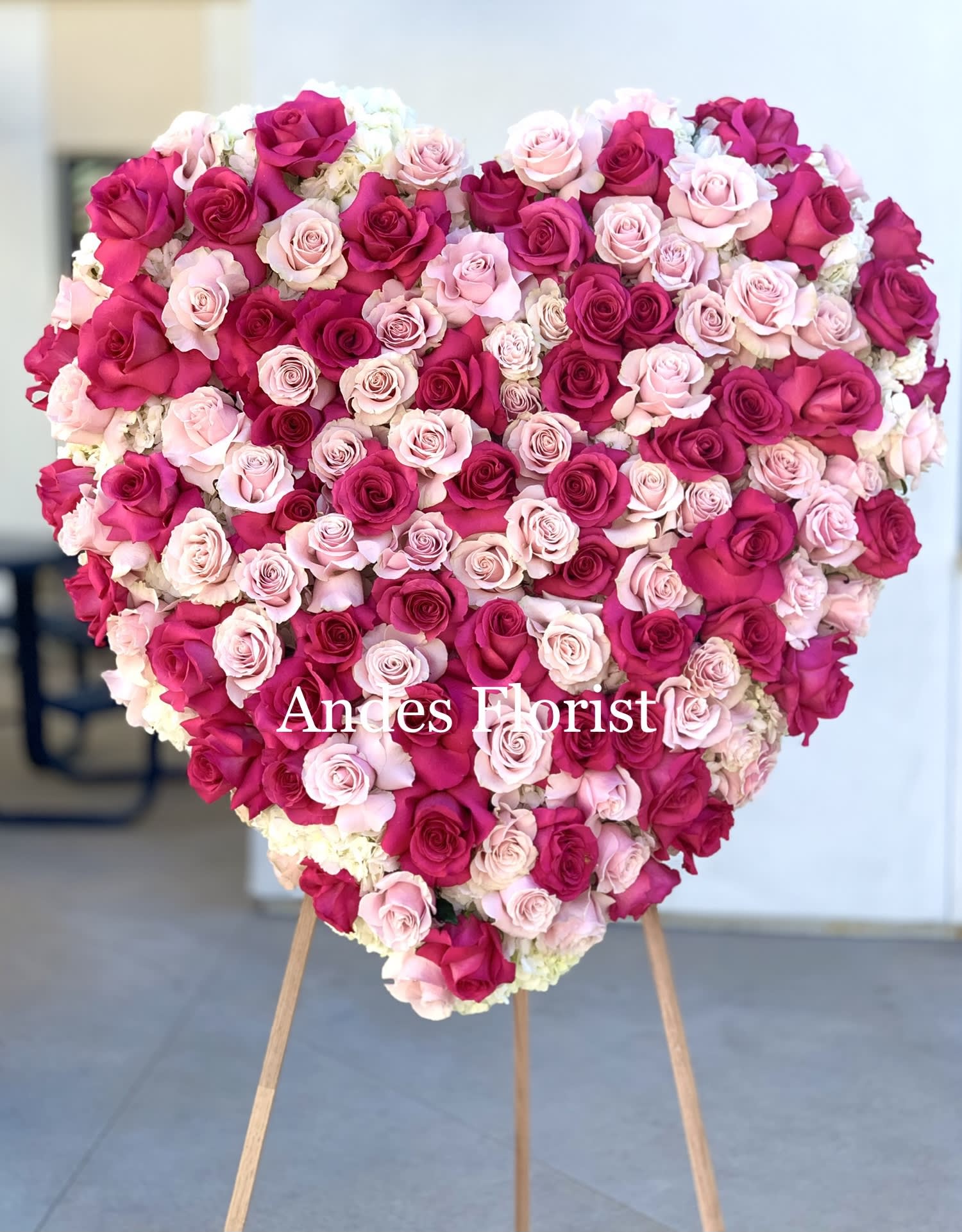 Heart-shaped arrangement of pink and magenta roses on an easel