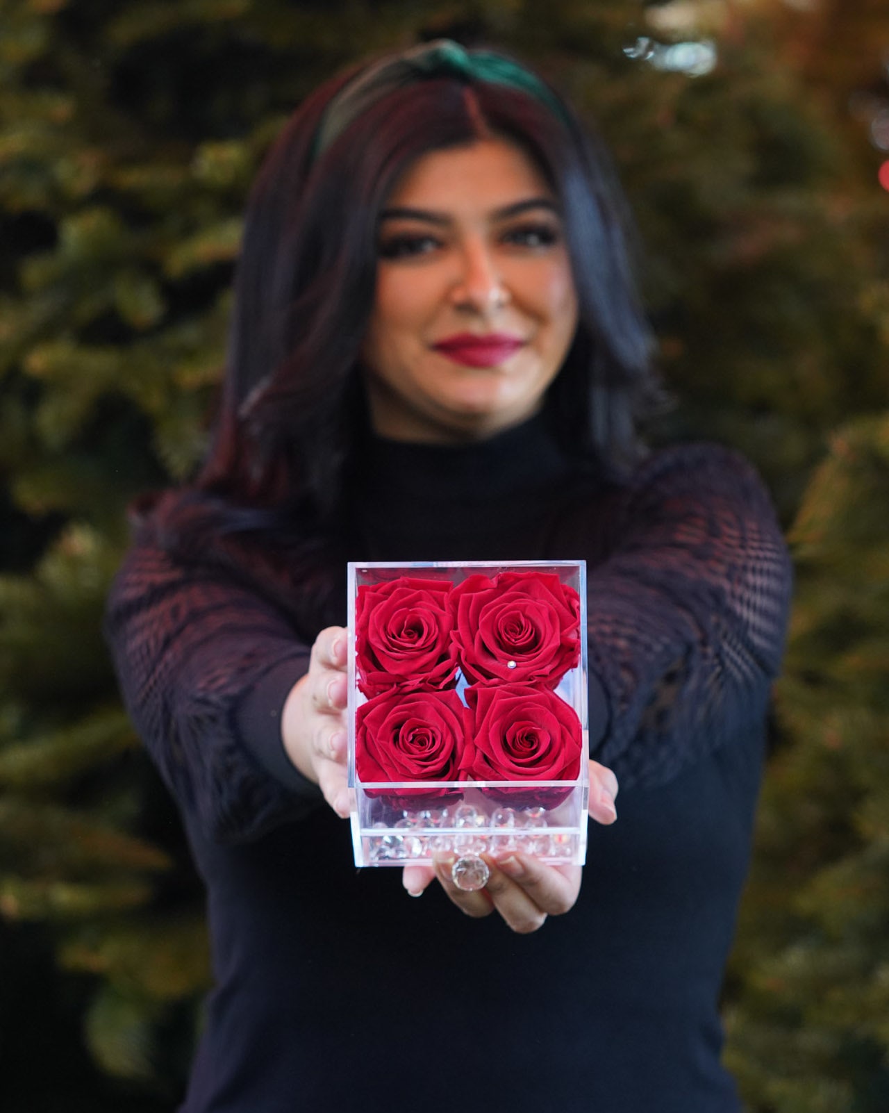 Woman holding a clear box of four red roses