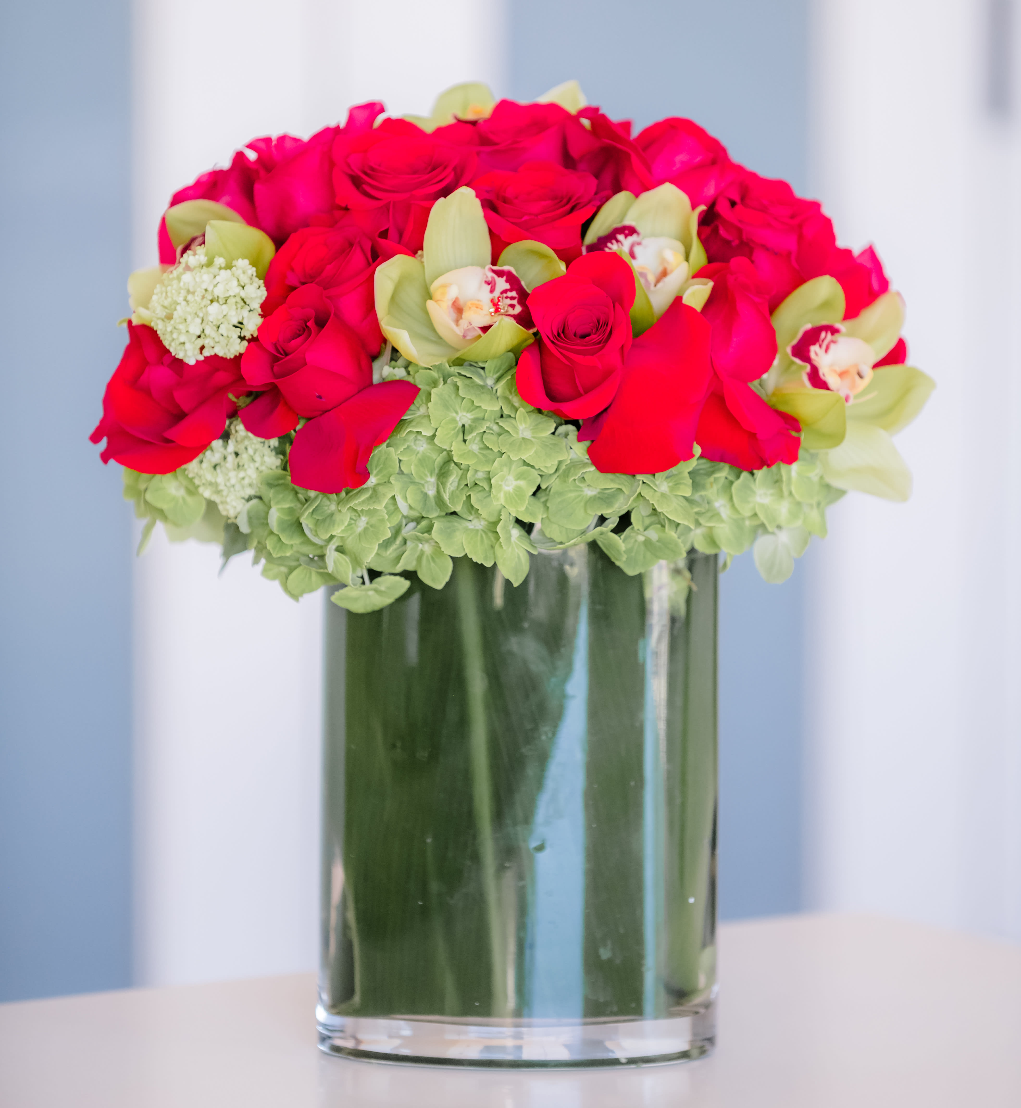 Bouquet of hot pink roses and green orchids in a glass vase