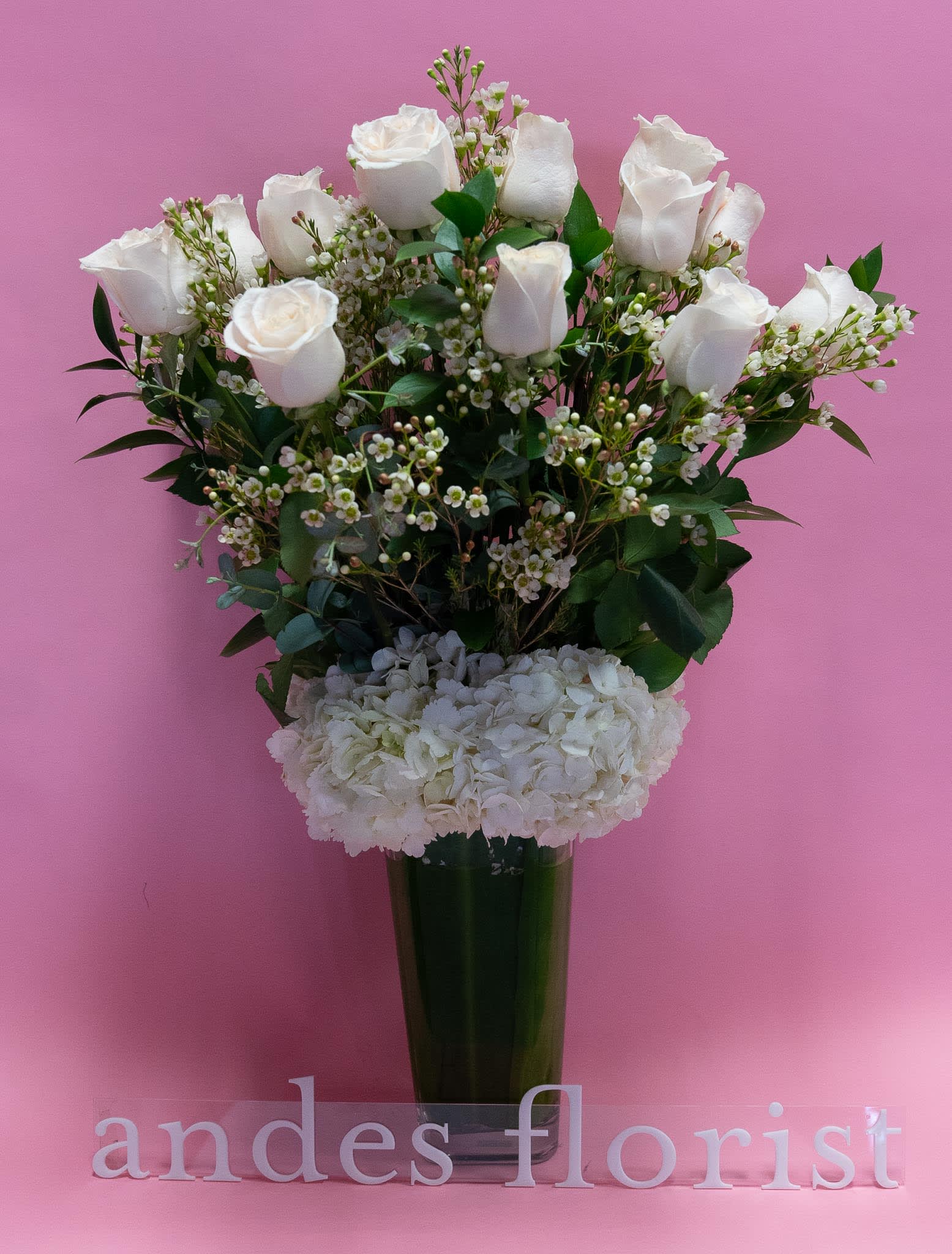 White roses and hydrangeas in a tall glass vase