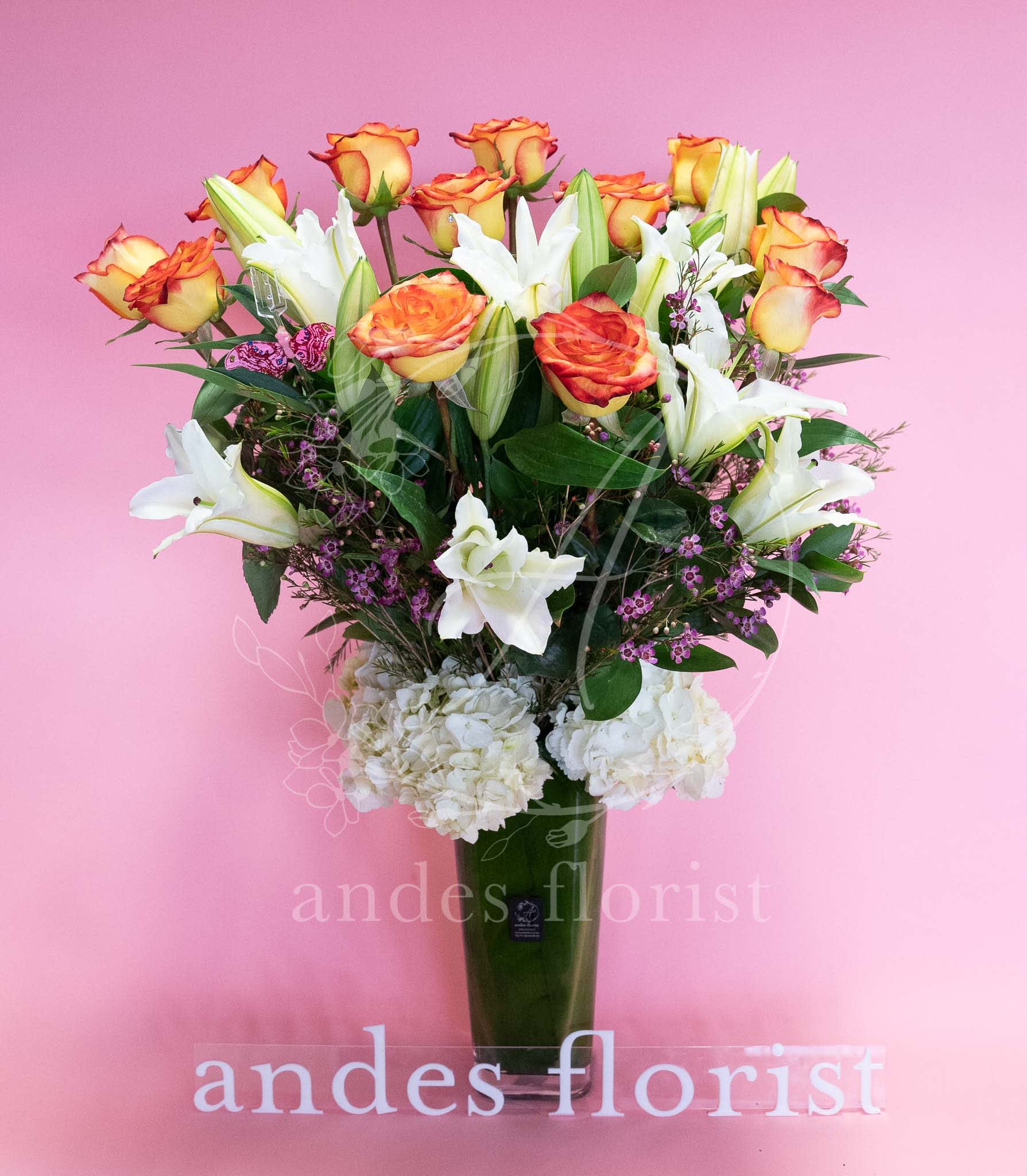 Bouquet of orange-edged roses and white lilies in a tall vase