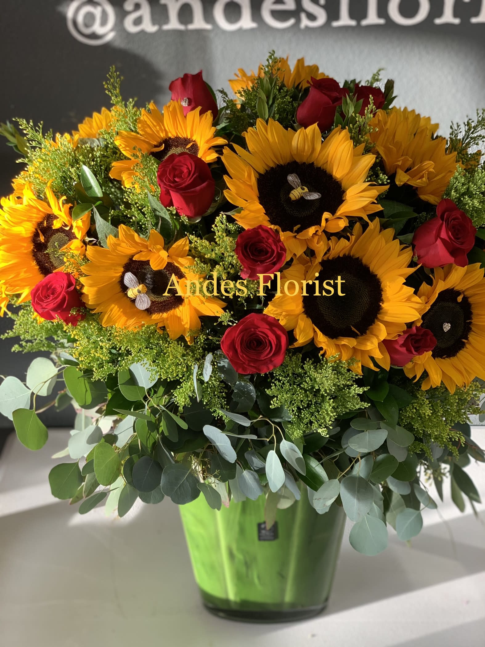 Sunflower and red rose arrangement in a green vase