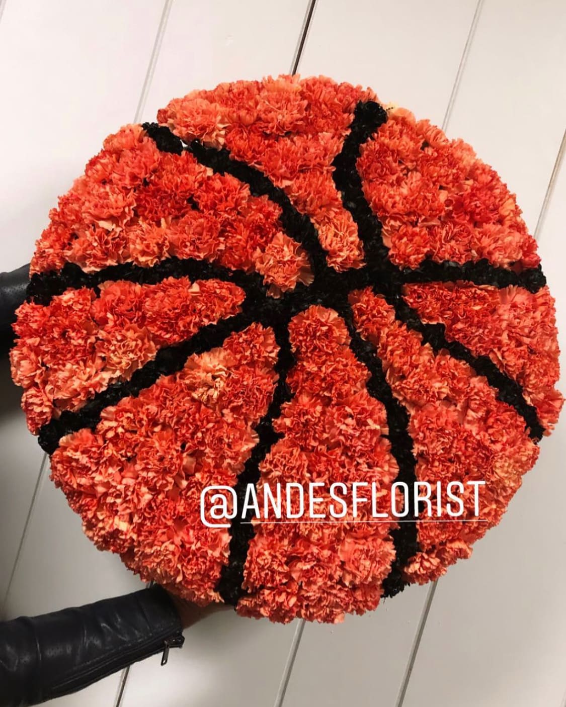 Basketball-shaped arrangement of orange carnations with black accents