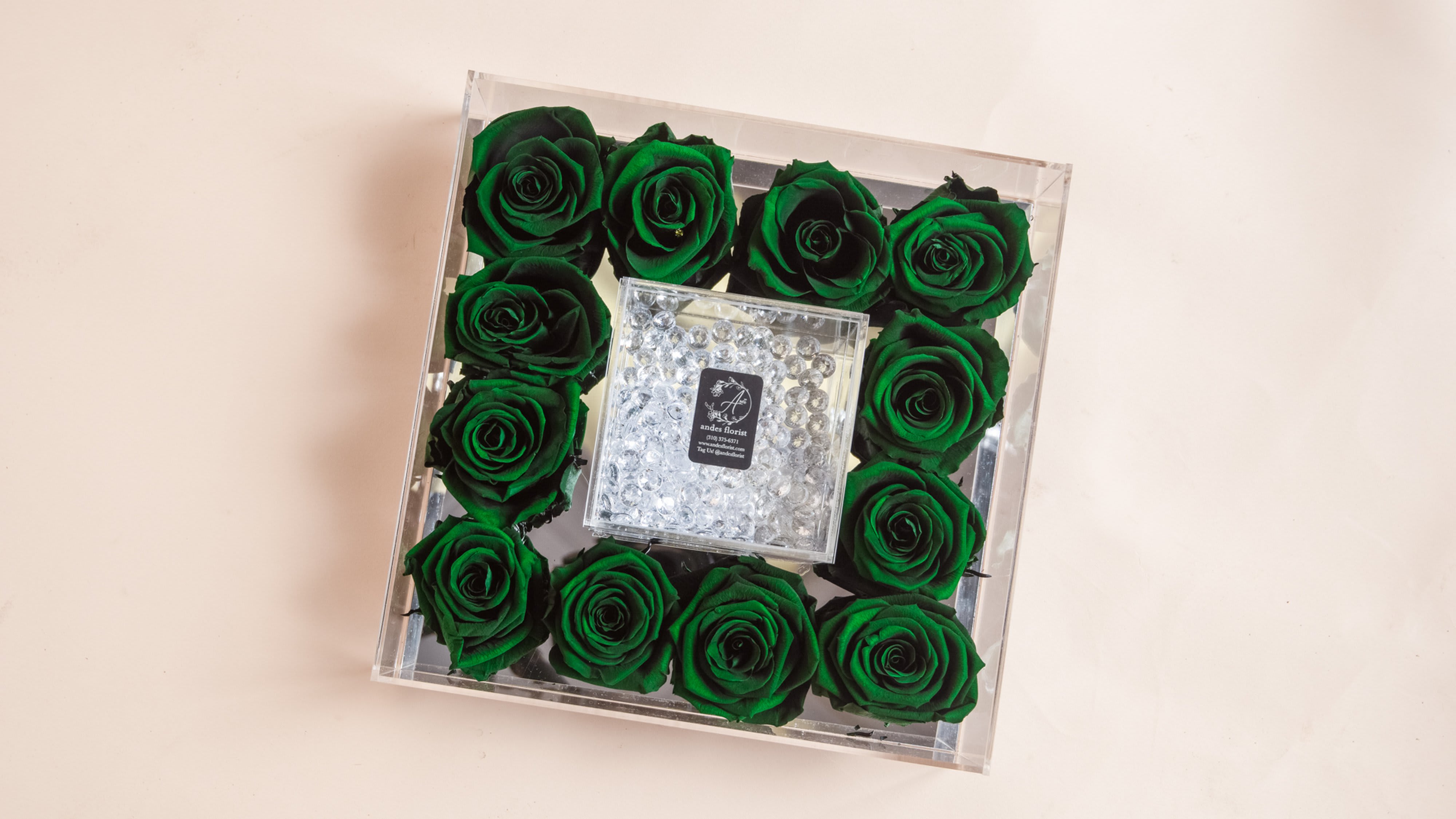 Green roses arranged in a clear square box with a crystal center