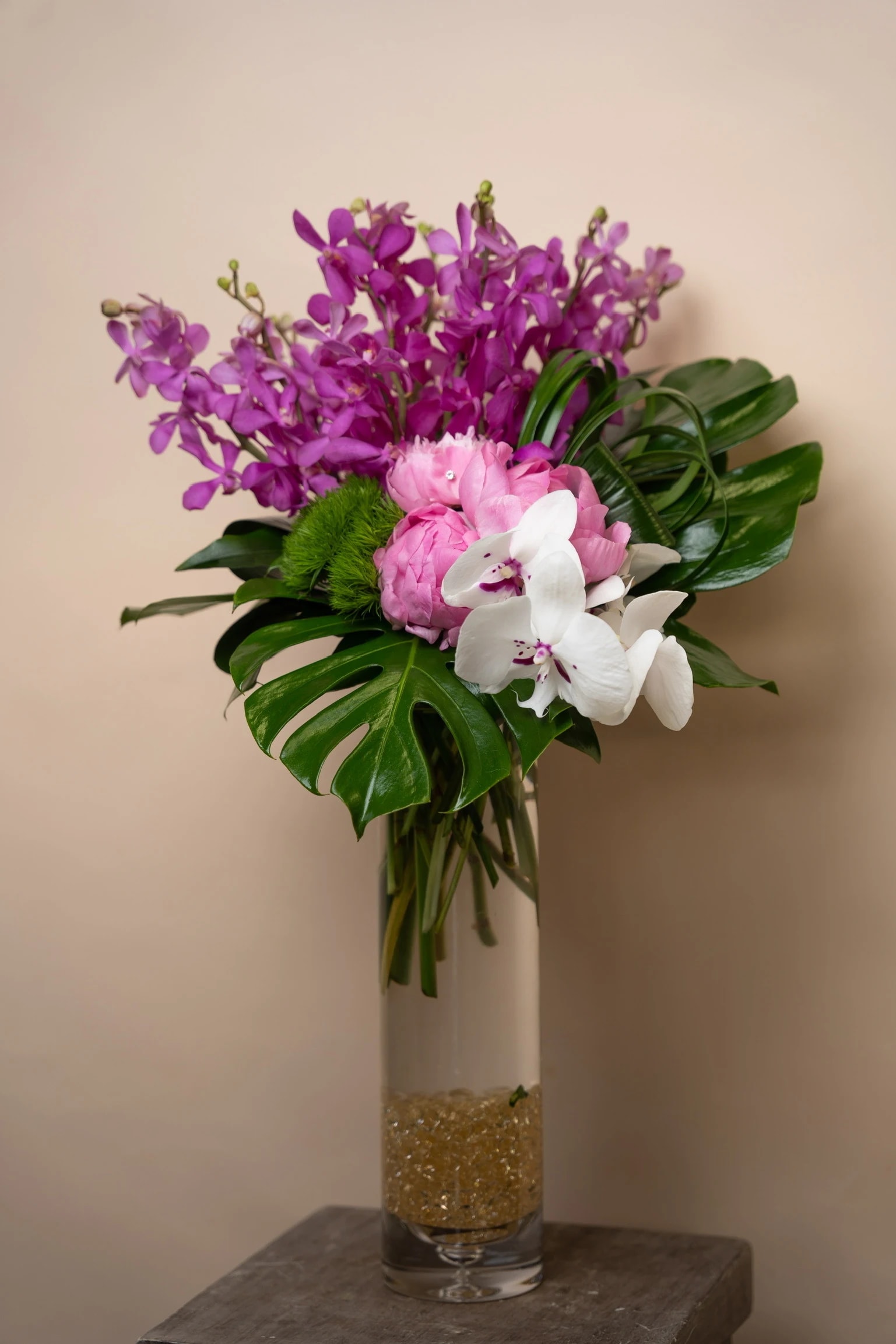 Purple and white orchid bouquet in a tall glass vase
