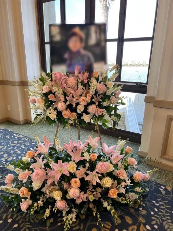 Large pink and peach floral funeral display on easels