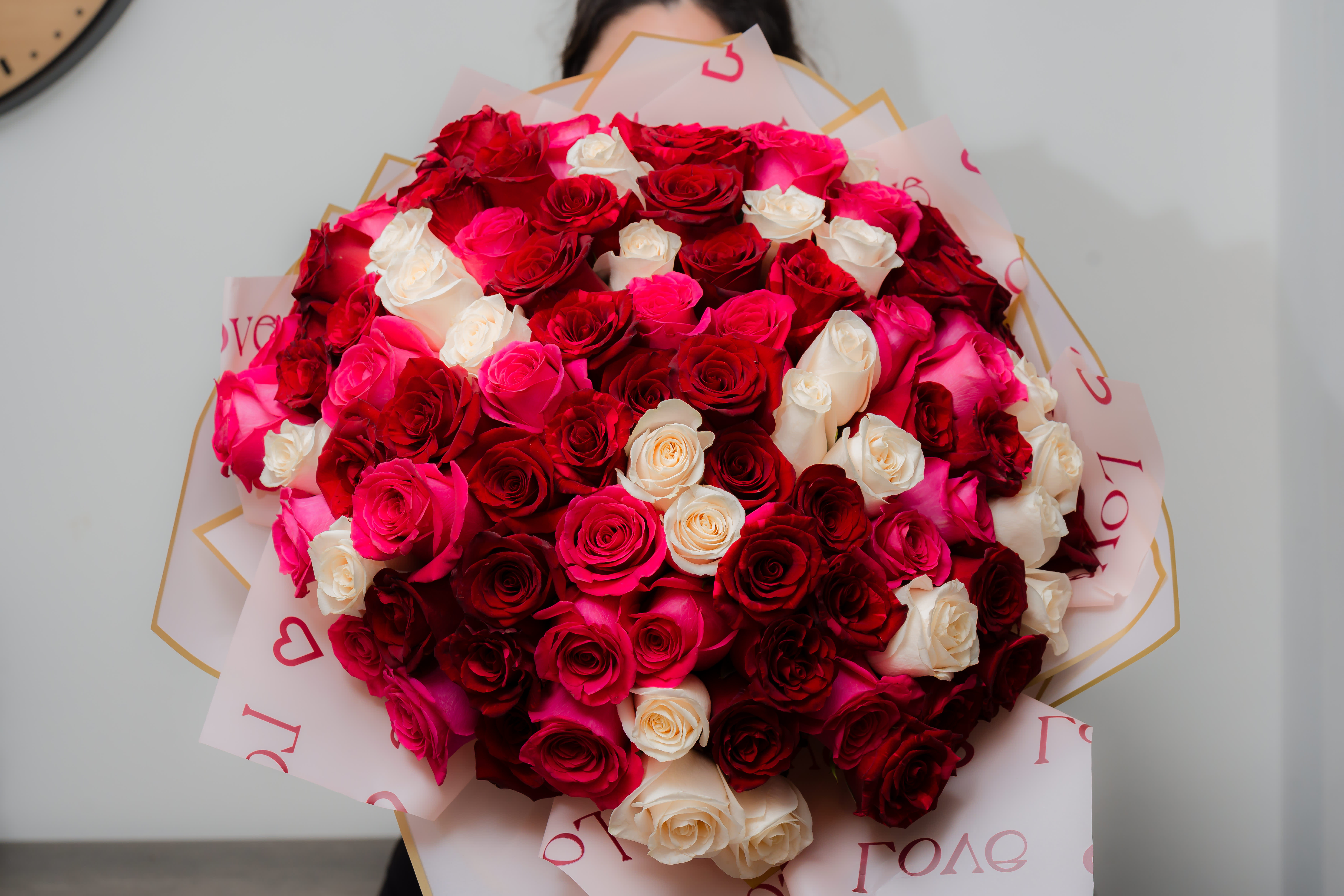 Large bouquet of red, pink, and white roses wrapped in printed paper