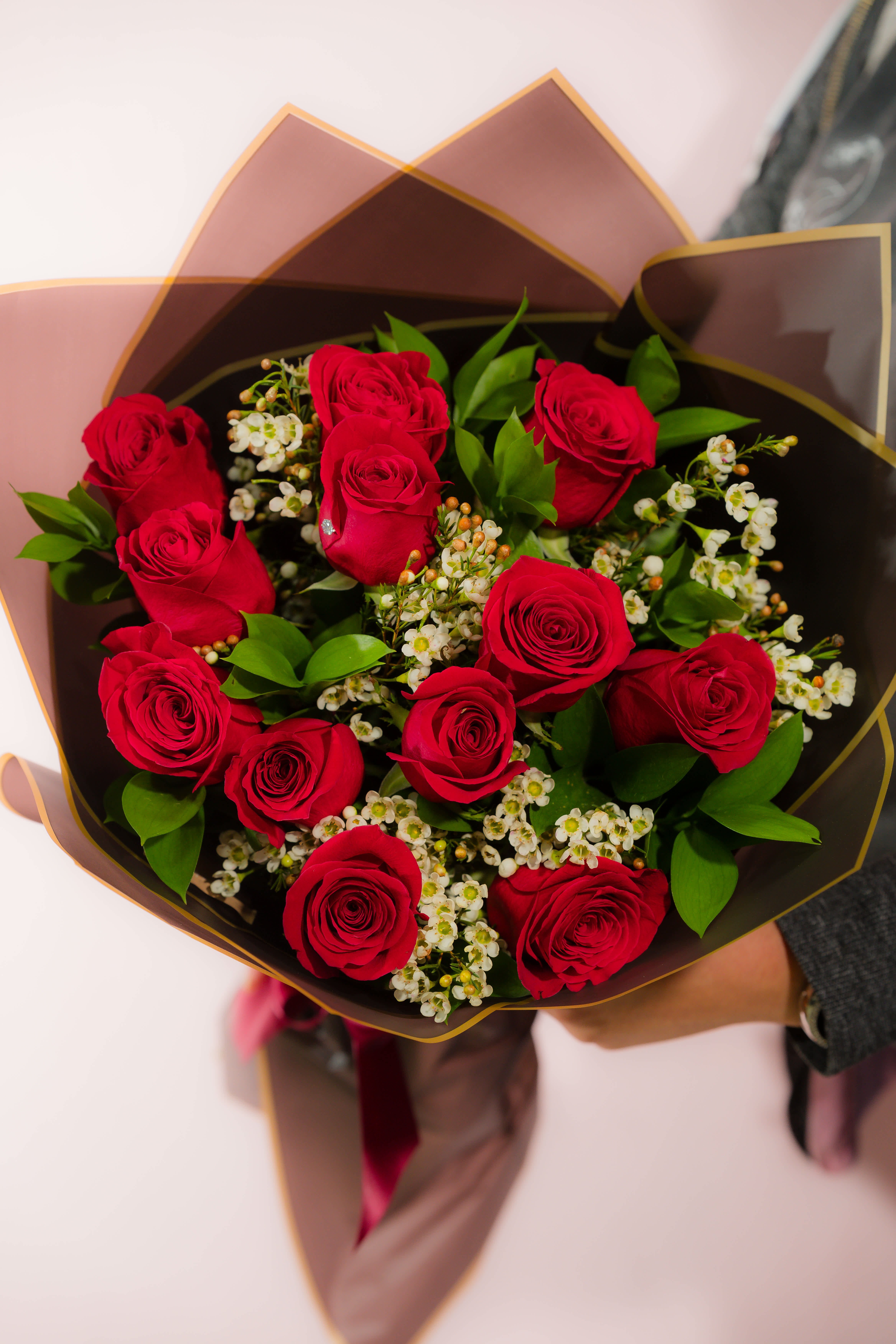 Bouquet of red roses with white filler flowers in dark wrapping