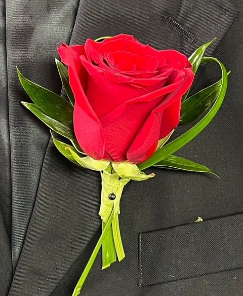 Red rose boutonniere pinned to a black suit jacket