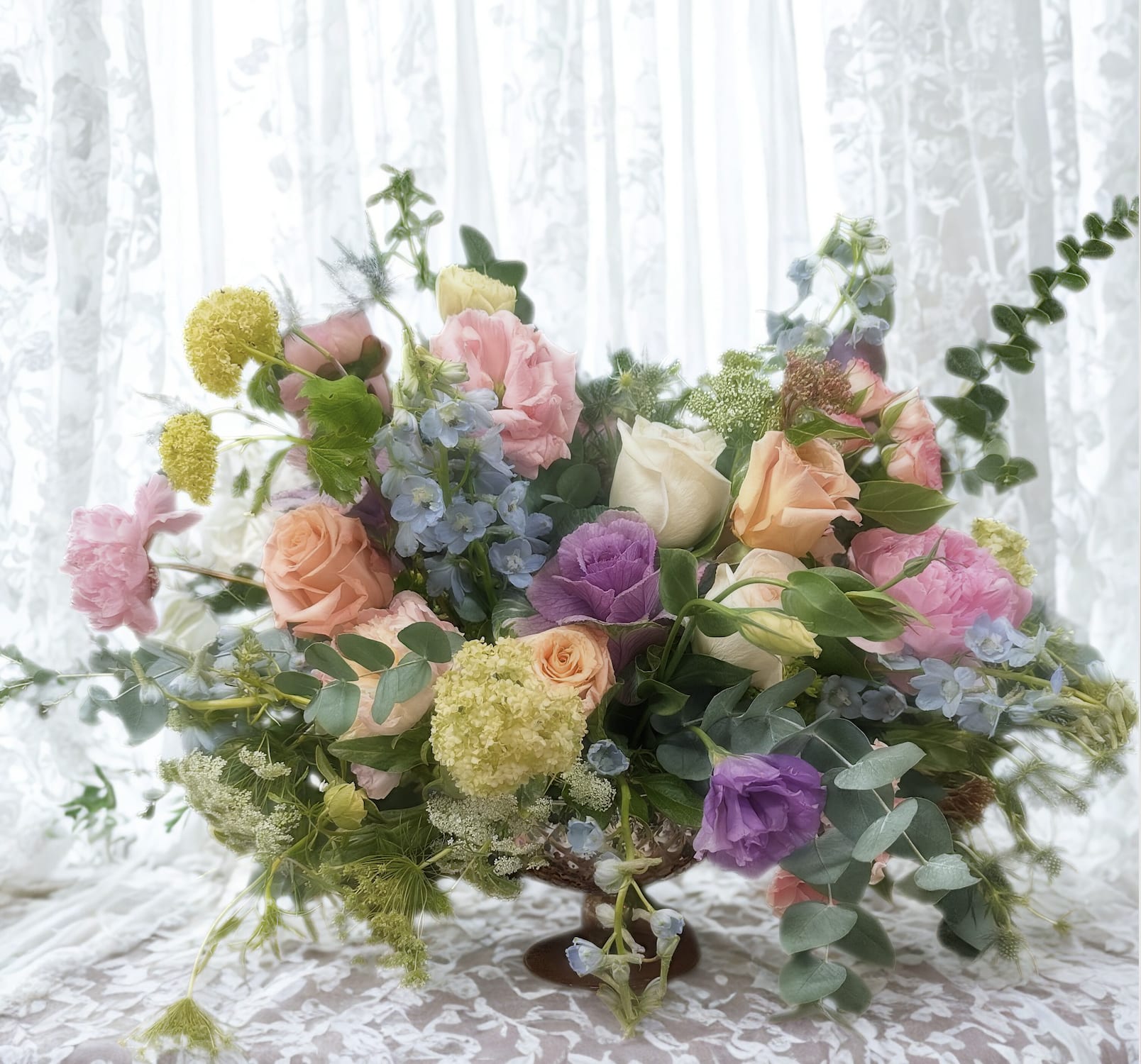 Mixed pastel flower arrangement in a low pedestal vase