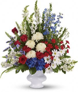Mixed red, white, and blue floral arrangement in a white vase