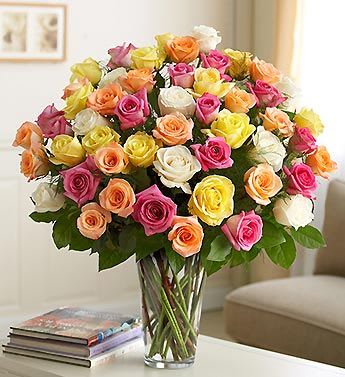 Mixed roses in pink, peach, yellow, and white in a clear glass vase