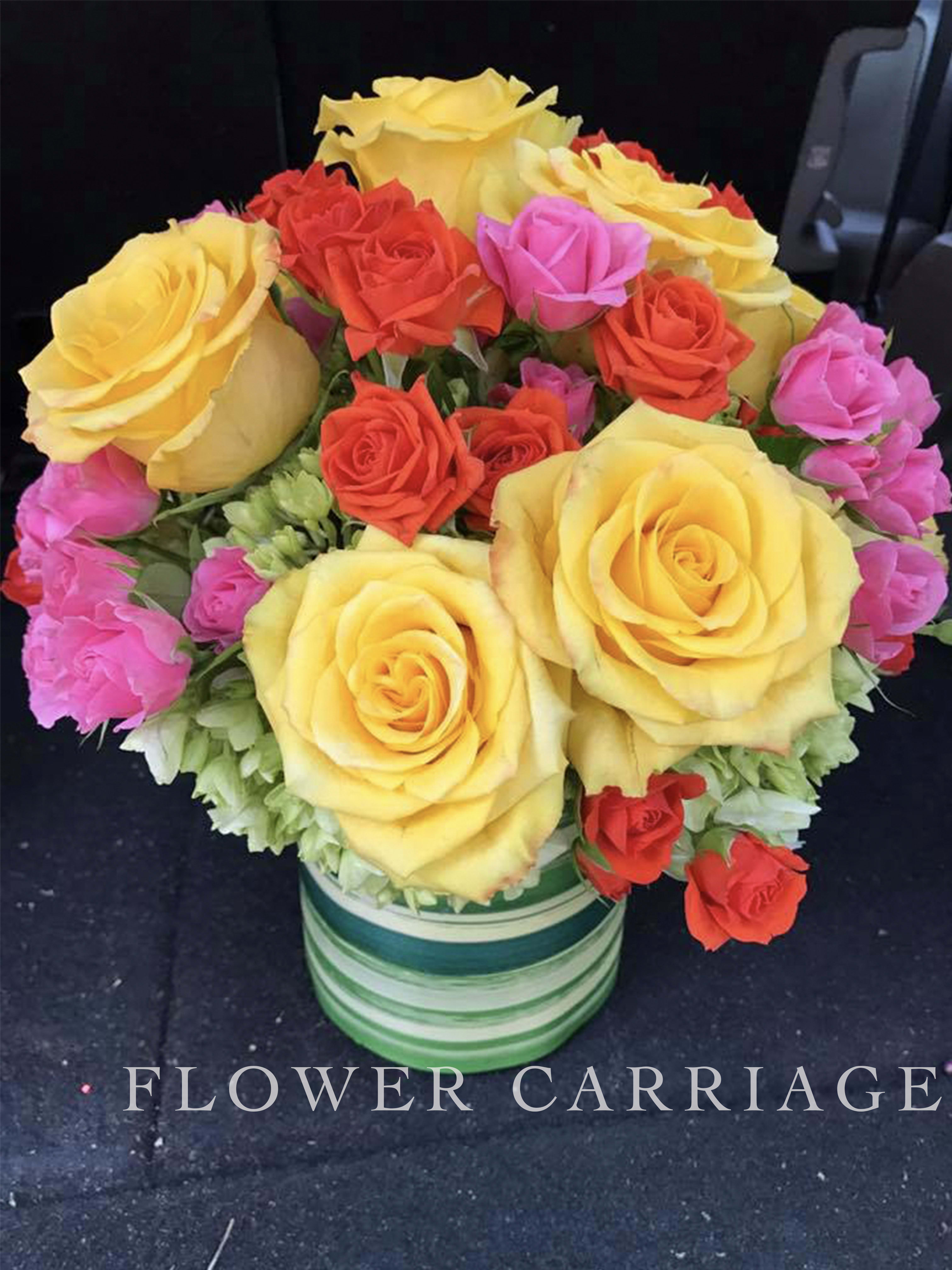 Bouquet of yellow, red, and pink roses in a striped vase