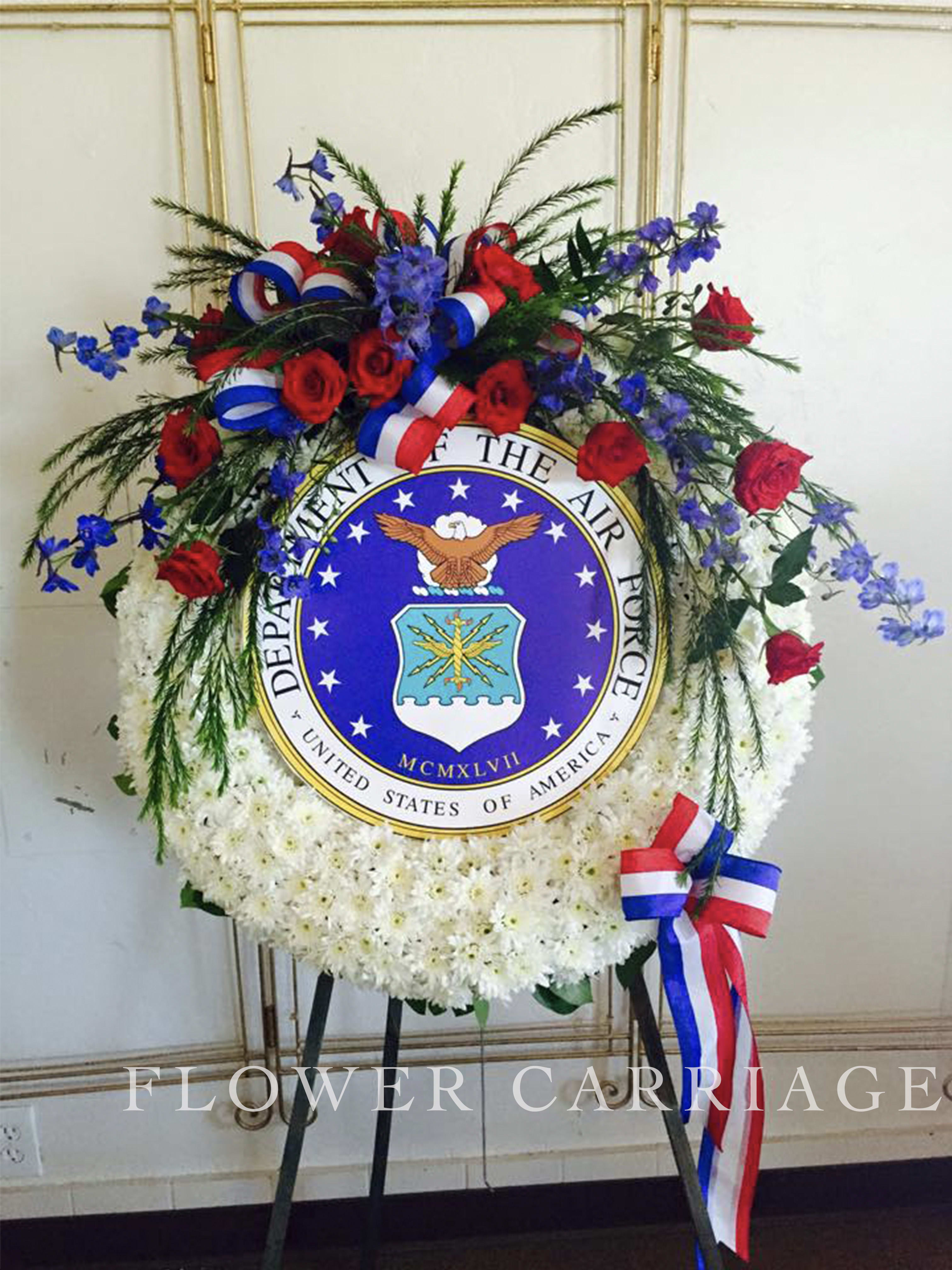 Circular floral wreath with red roses, white flowers, and blue accents around an Air Force emblem