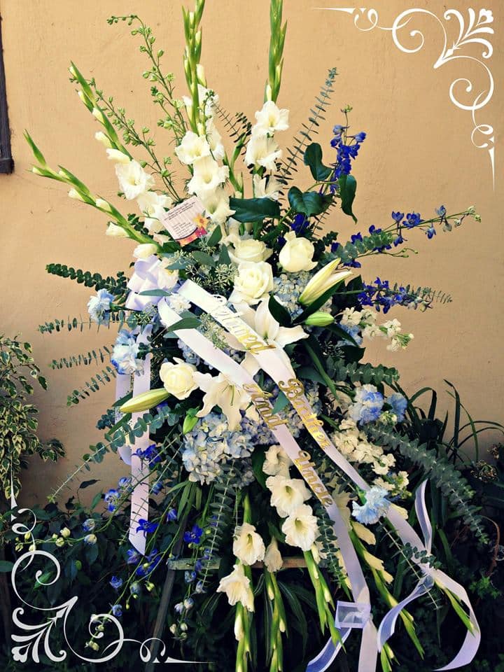 Tall white floral spray with blue accents and ribbon streamers