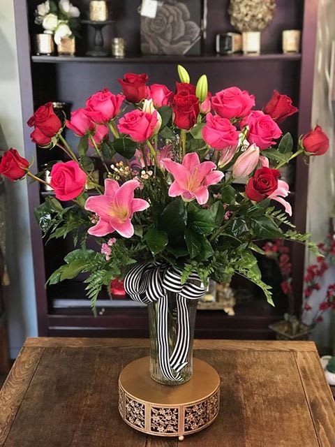 Pink and red roses with pink lilies in a glass vase