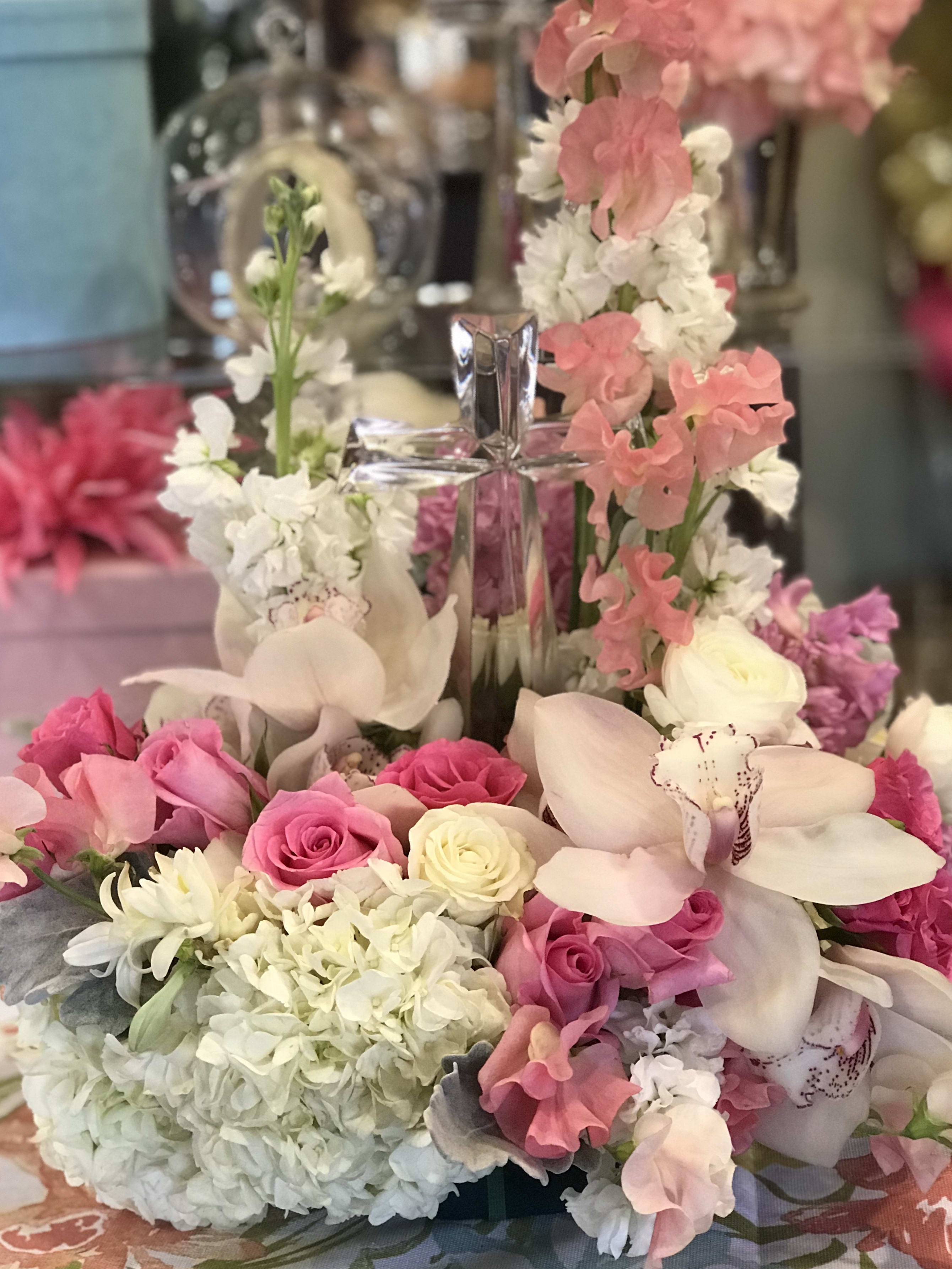 Pink and white floral arrangement with a clear cross centerpiece
