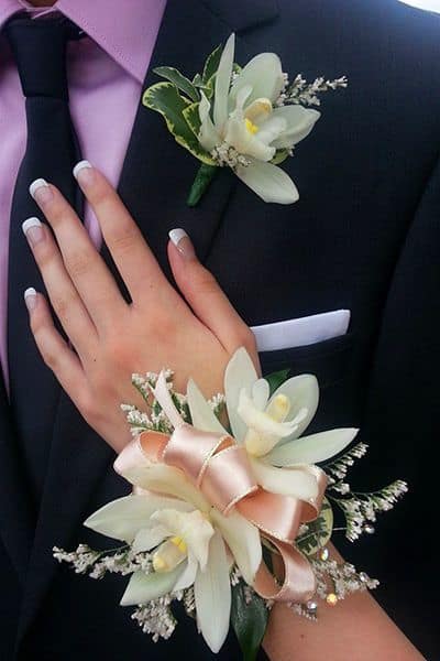 White floral corsage and boutonniere on a dark suit