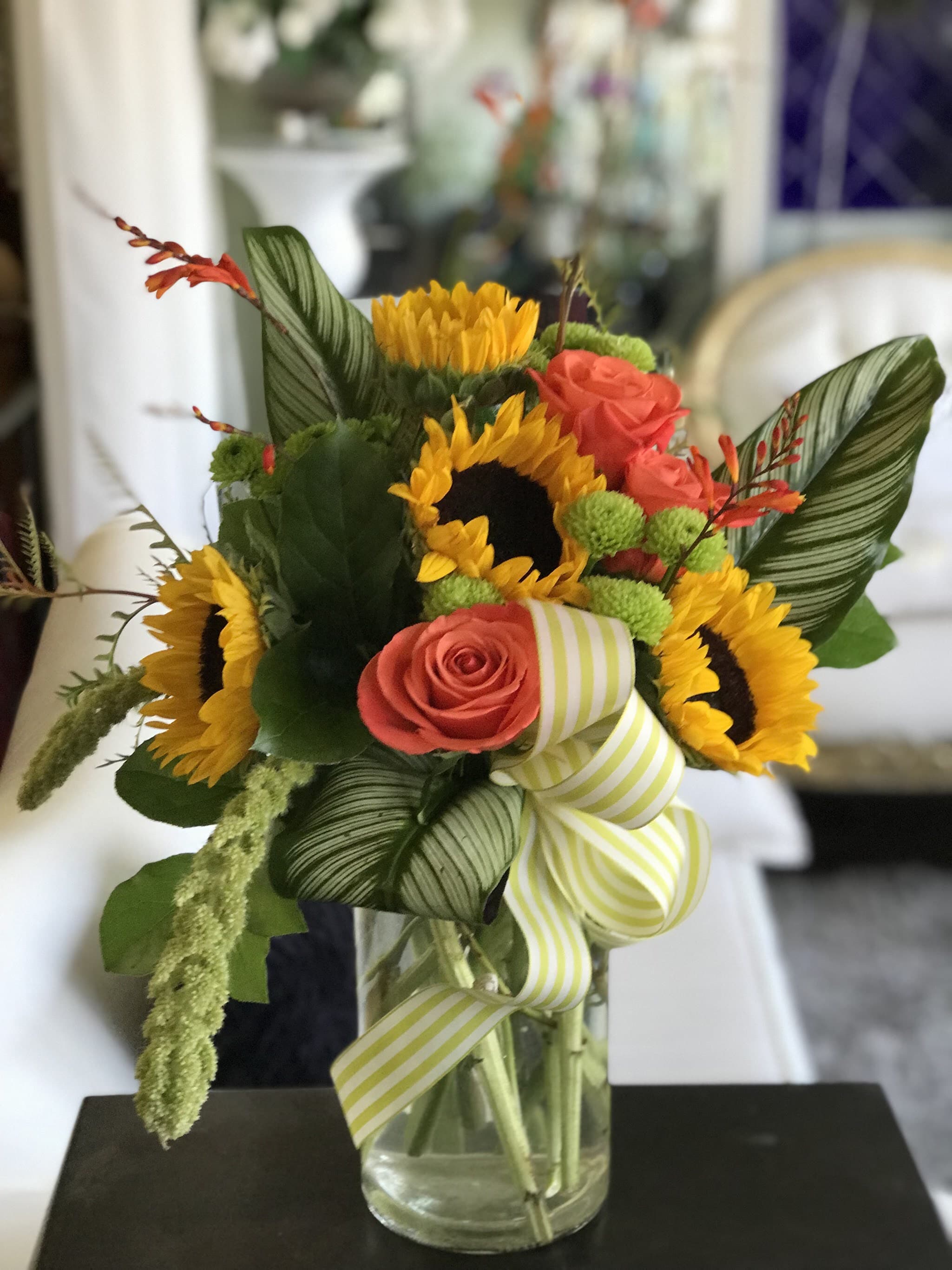 Tropical Feels - You are sure to feel right in the tropics with this arrangement! This arrangement features: Sunflowers, roses, green buttons, tropical leafs.