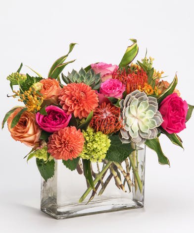 Mixed bouquet of pink and orange flowers in a clear glass vase