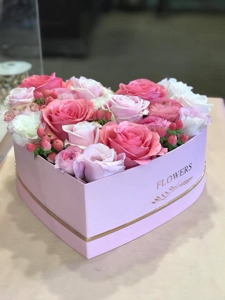 Pink and white roses arranged in a heart-shaped box