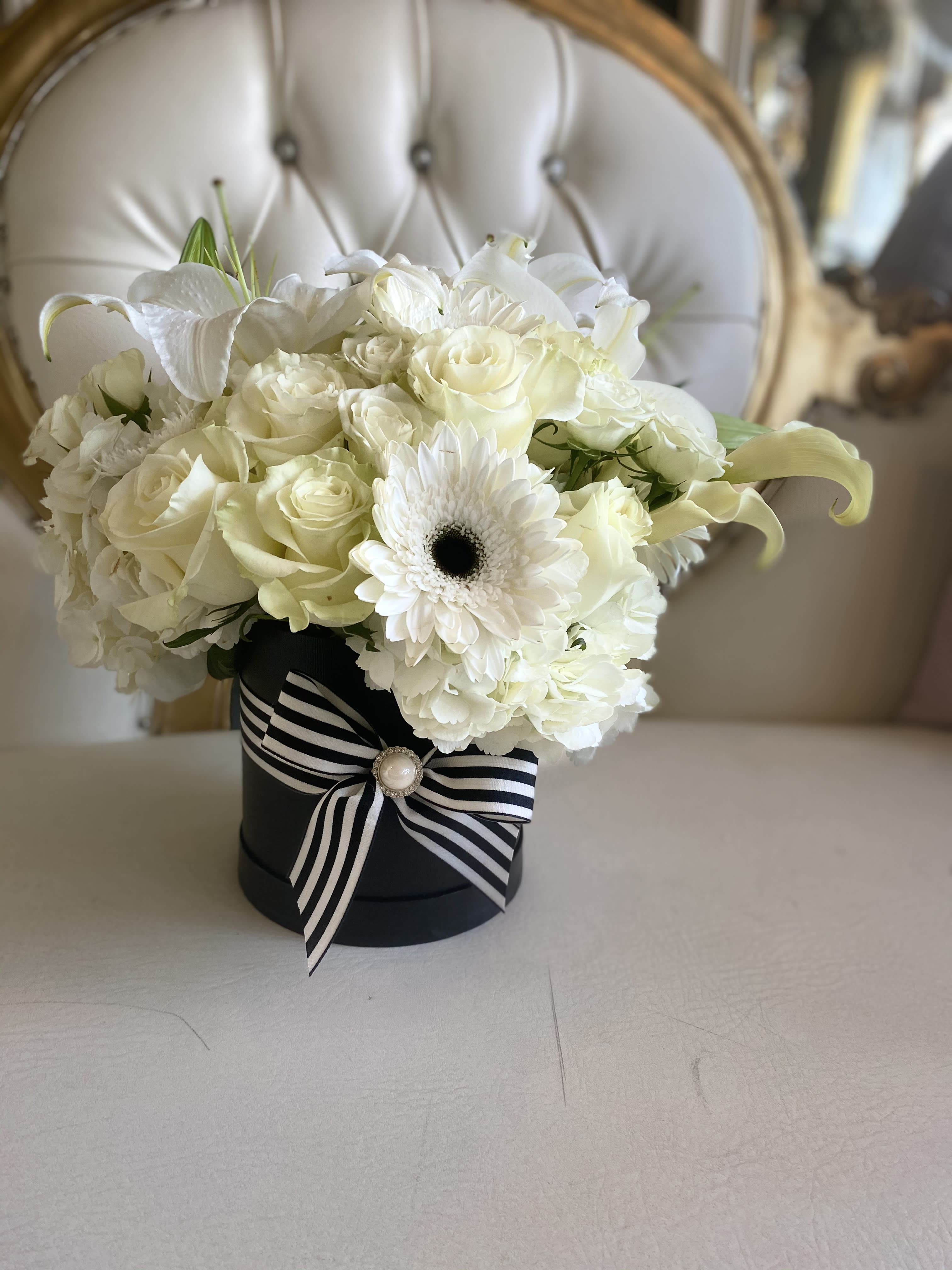 White rose and lily bouquet in a black hat box with striped ribbon