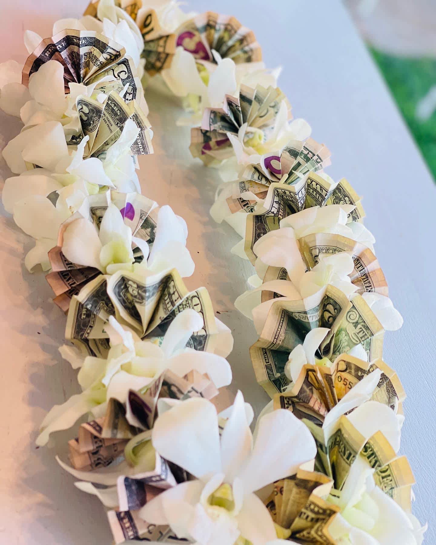 White flower garland with folded dollar bills woven into each bloom
