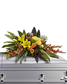 Bright mixed floral spray on a white casket
