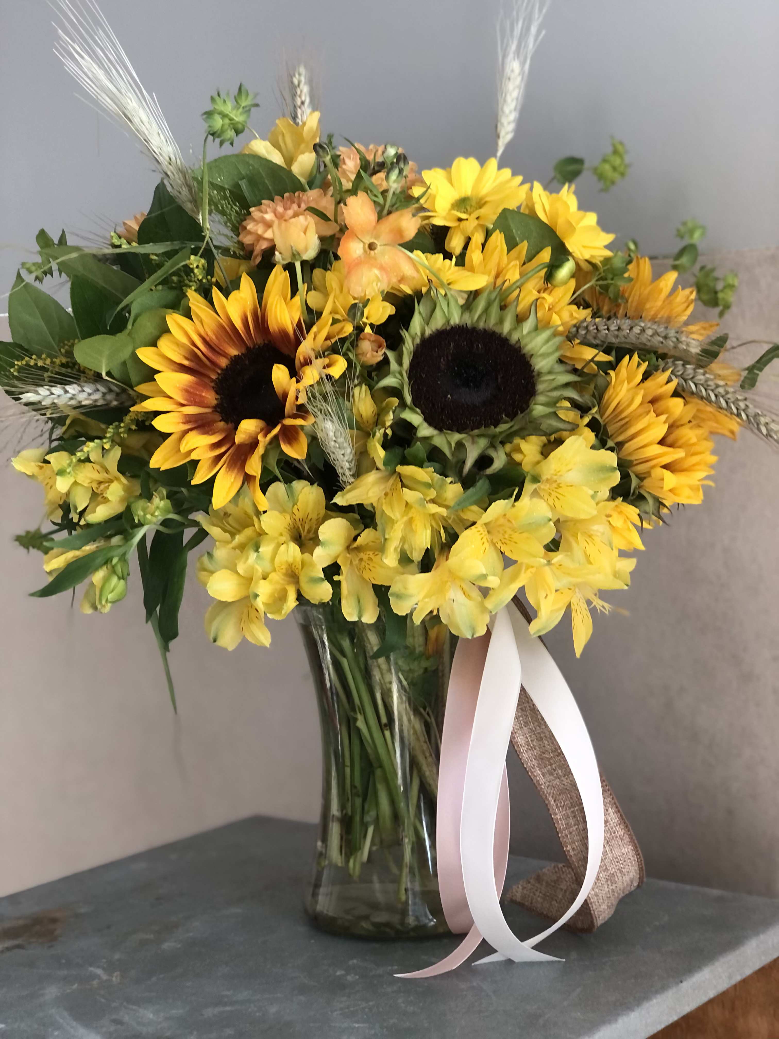 Yellow sunflower bouquet in a glass vase with ribbon