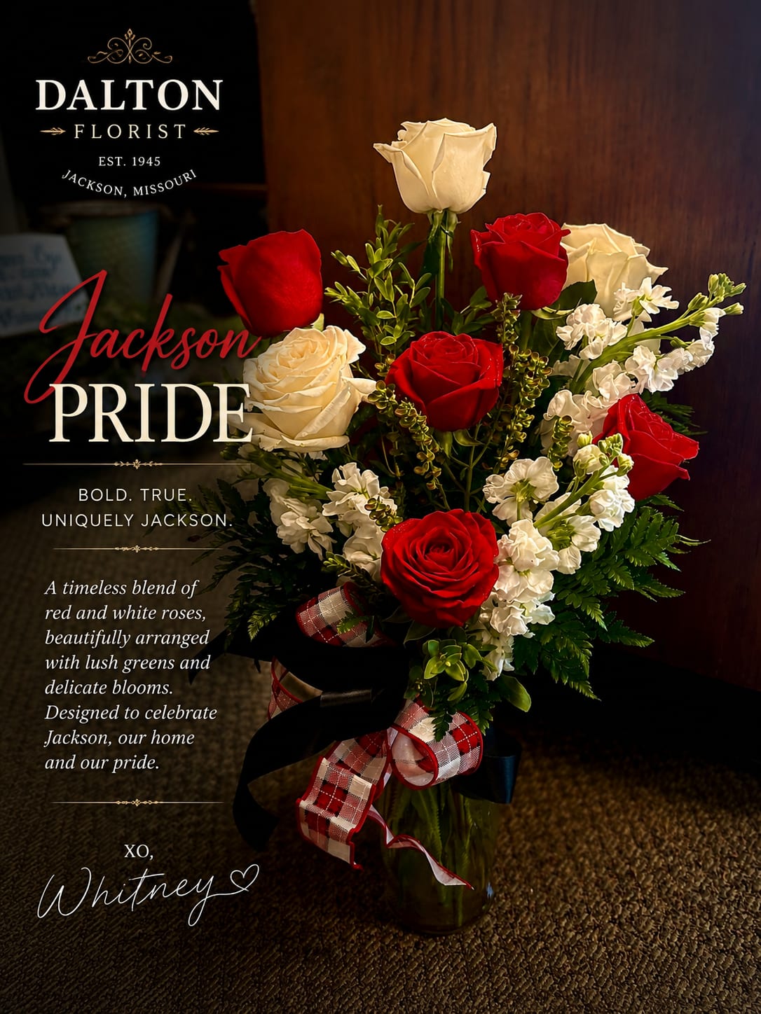 Red and white roses arranged in a glass vase with a plaid ribbon