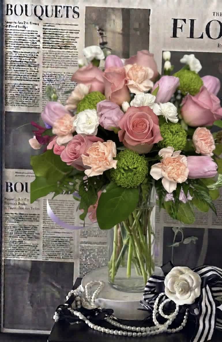 Pink and peach bouquet with roses, tulips, carnations, and green pom flowers in a glass vase