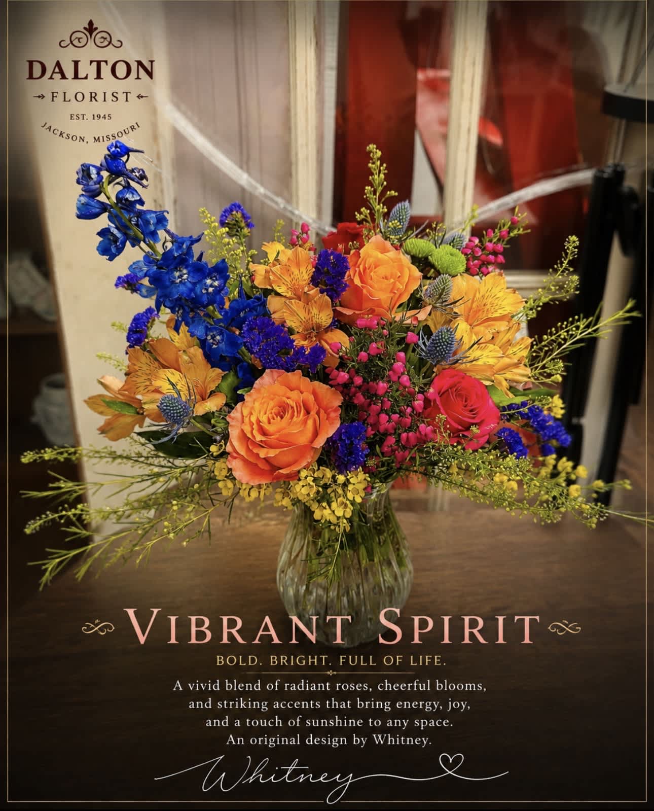 Bright mixed bouquet in a clear glass vase with orange, blue, and pink flowers