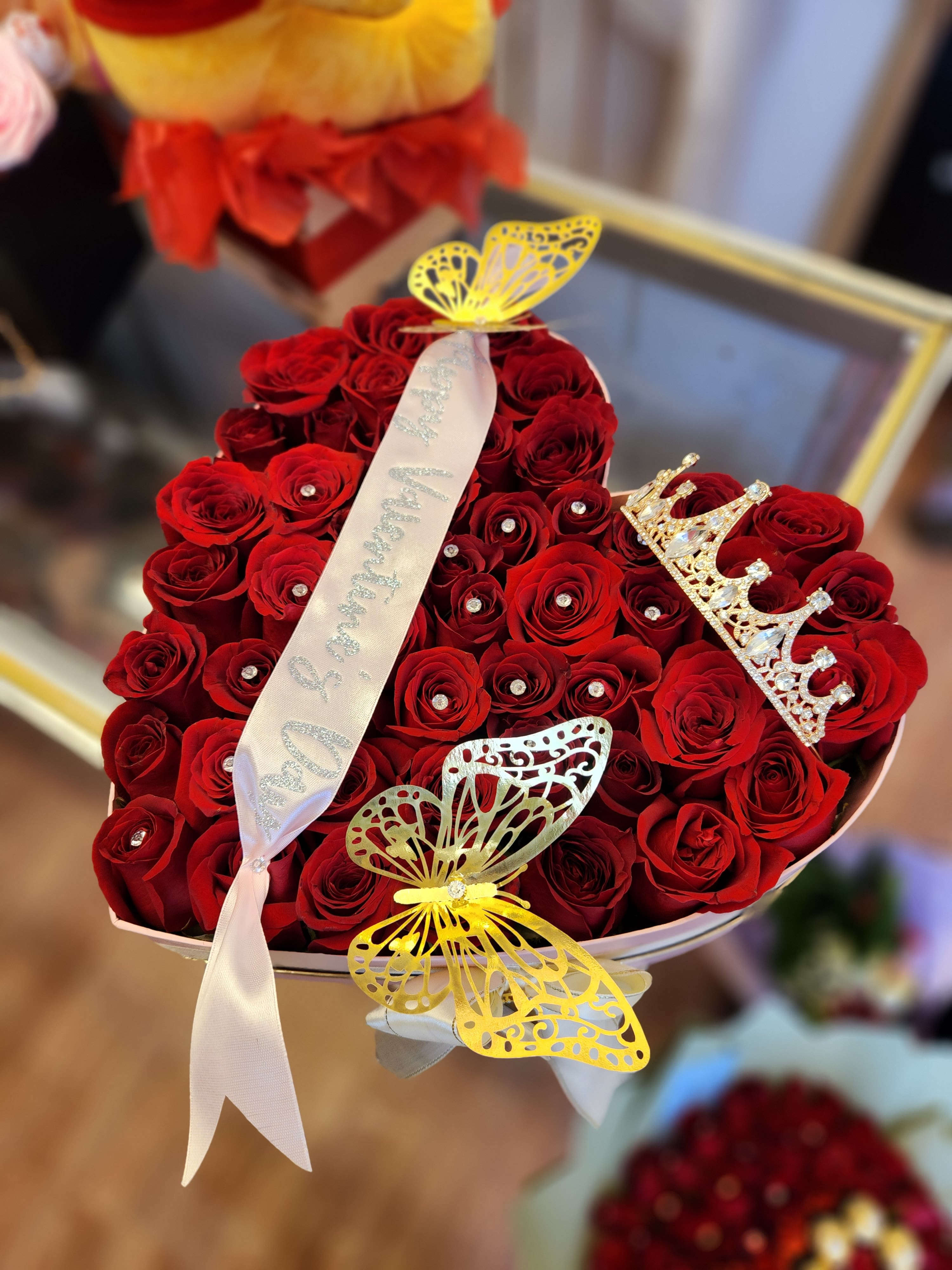 Heart-shaped bouquet of red roses with butterfly decorations and a ribbon
