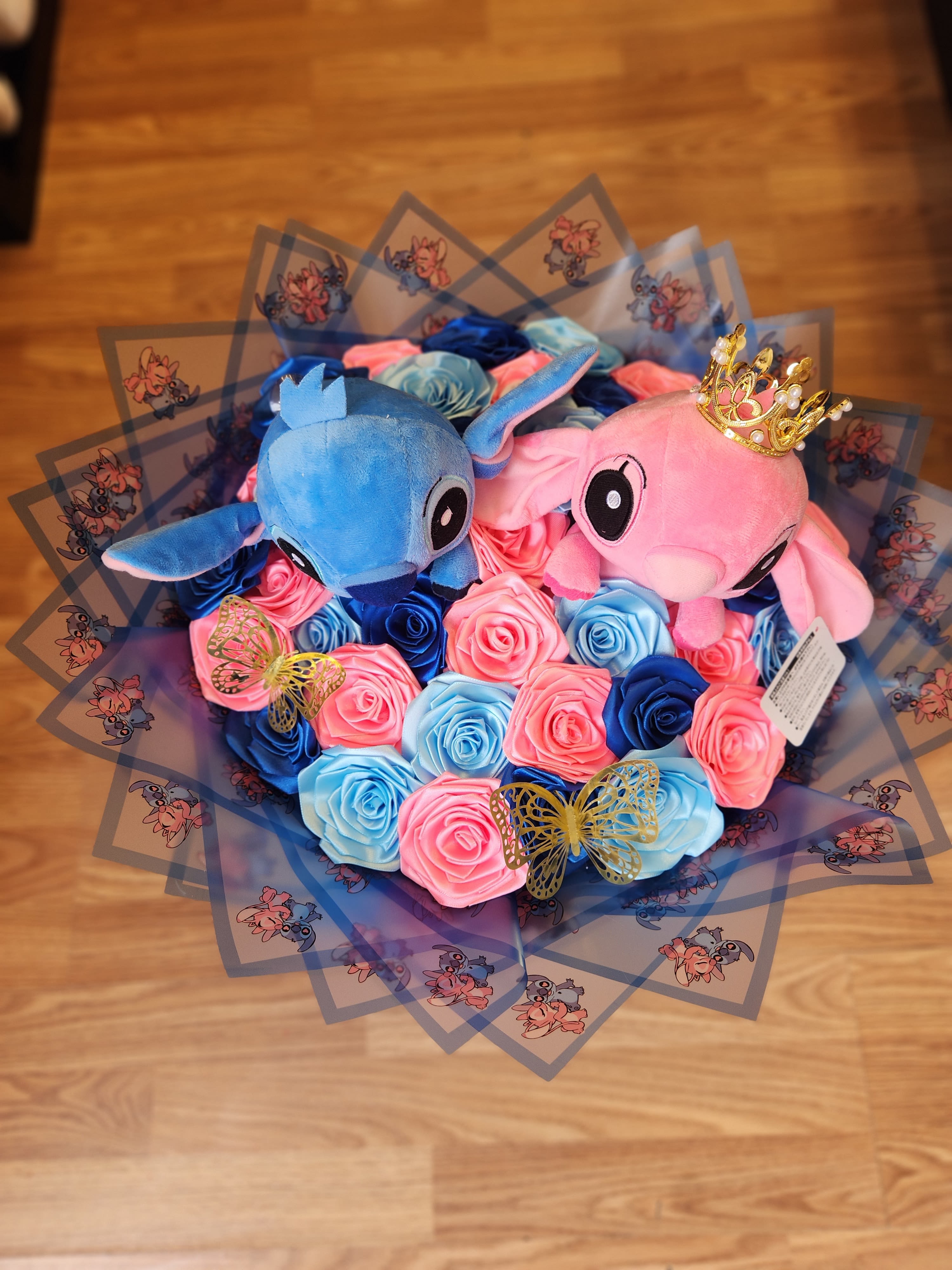 Bouquet of blue and pink roses with two plush characters and butterfly wrap