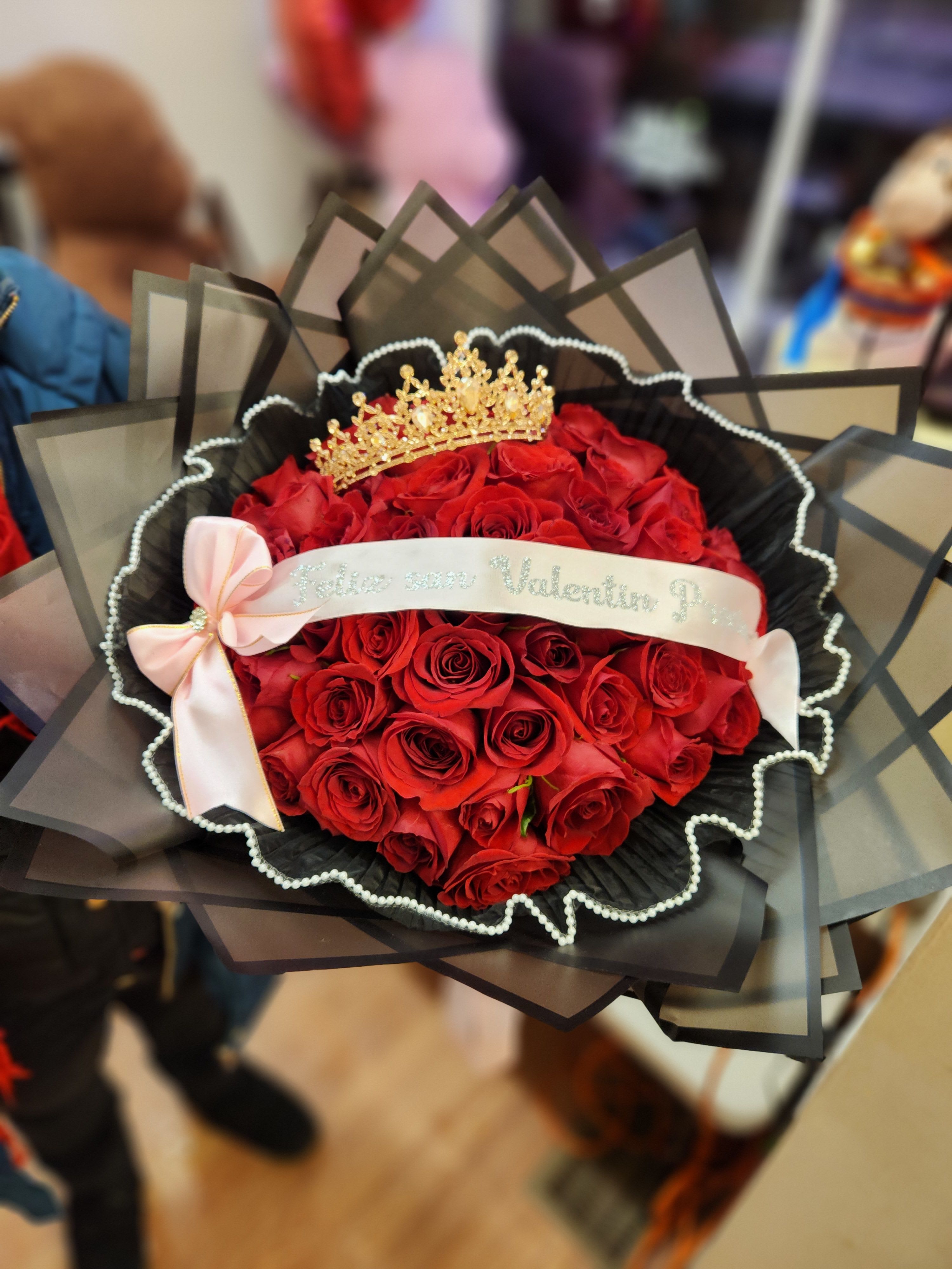 Bouquet of red roses with a gold crown and pink ribbon