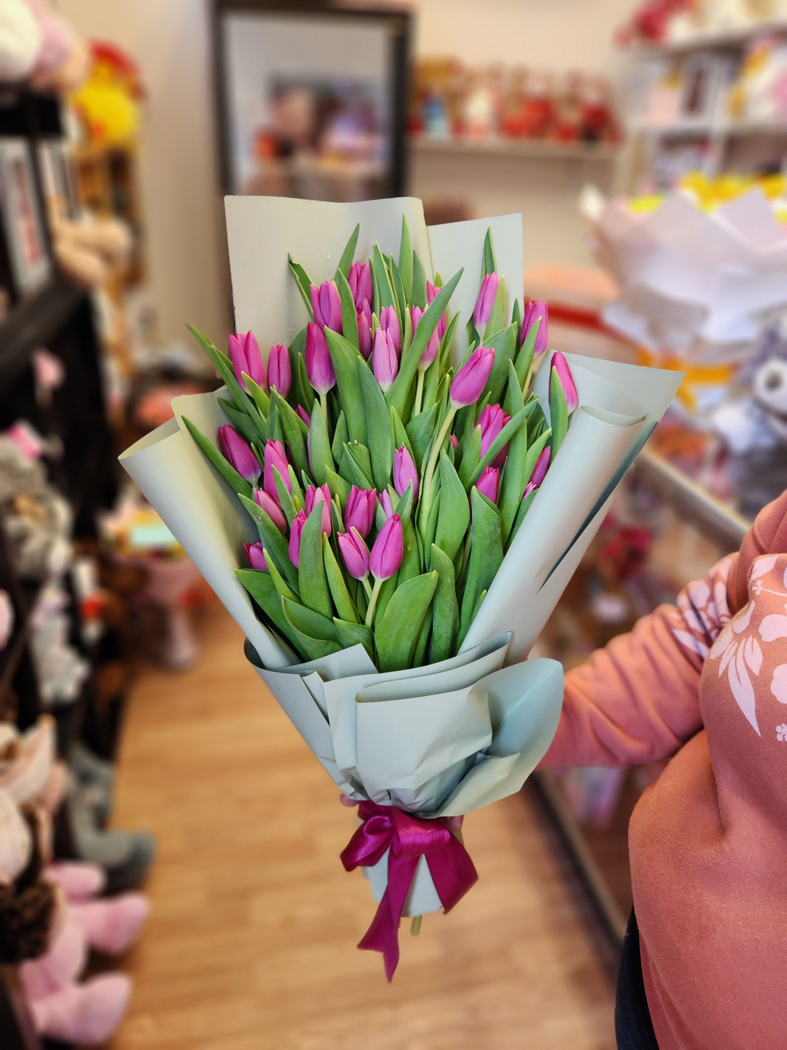 Bouquet of pink tulips wrapped in pale paper with a ribbon