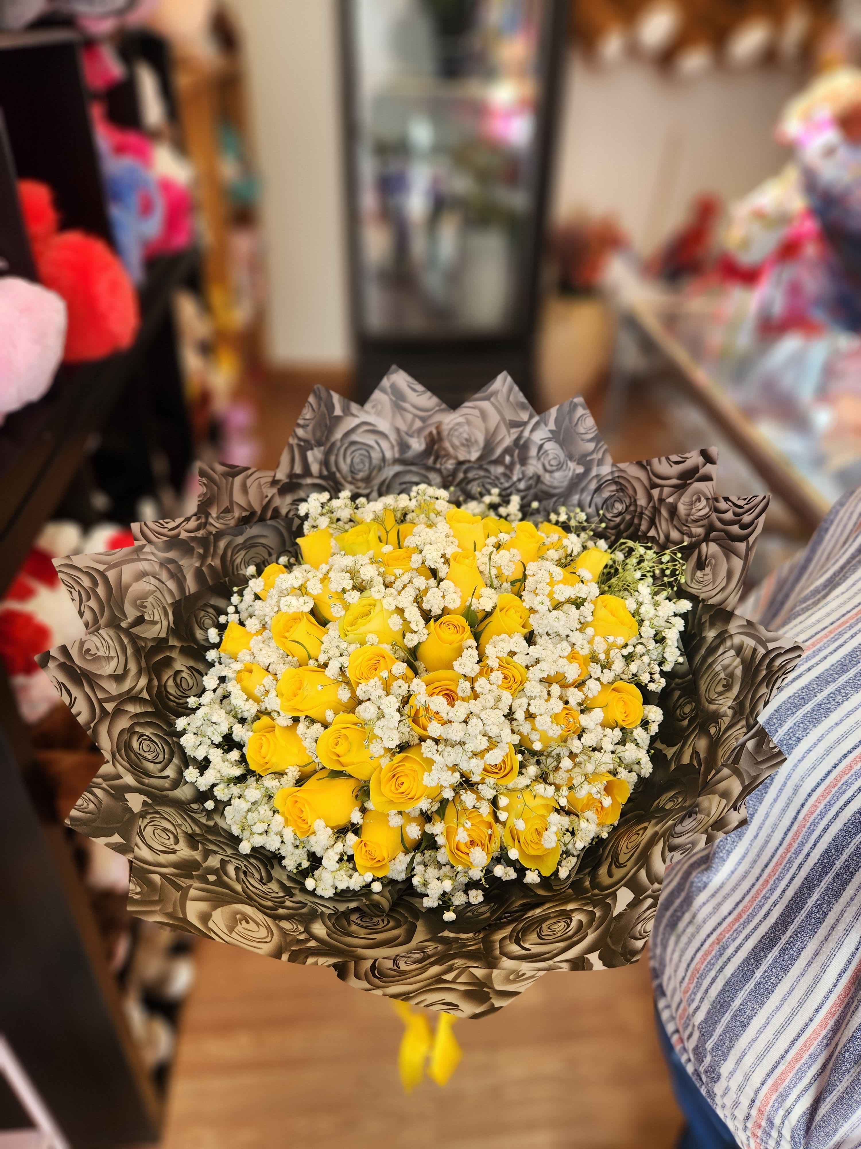 Bouquet of yellow roses with white baby's breath in patterned wrap